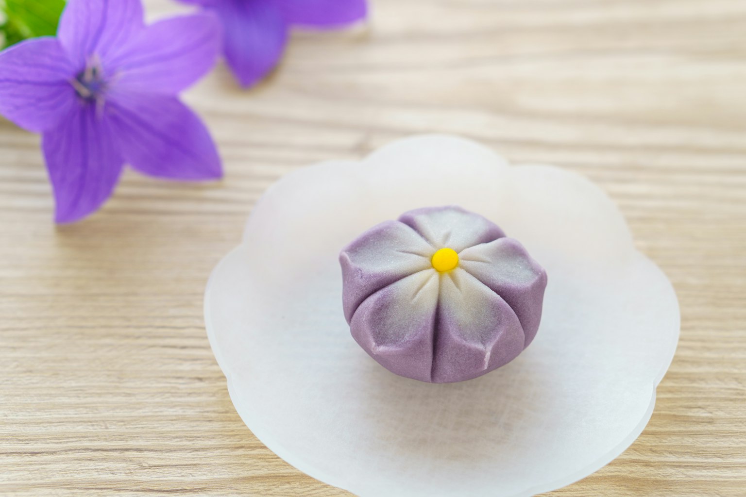 白色盤子上的紫色花朵形狀的和菓子