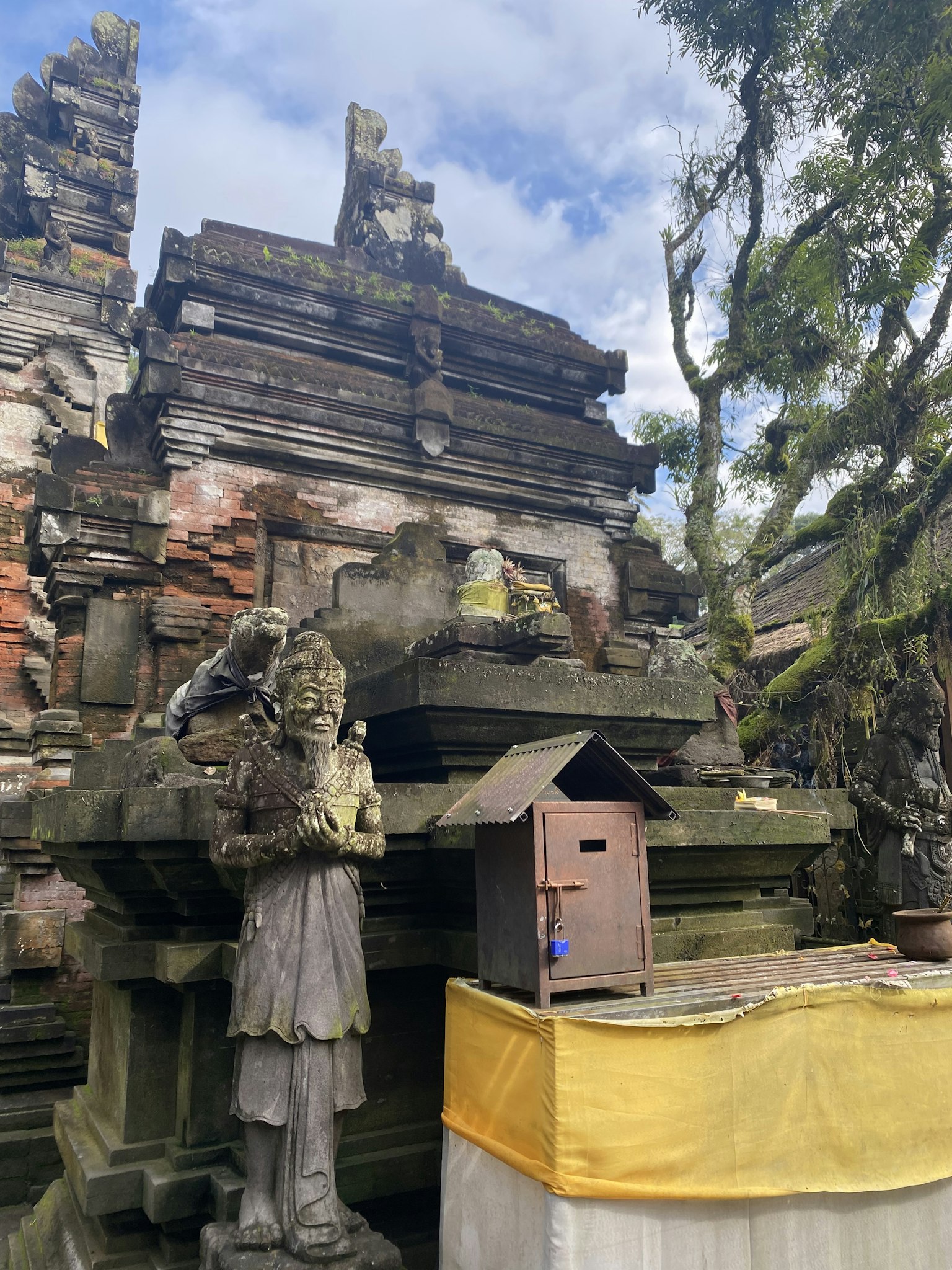 Scène d'un temple balinais avec des sculptures en pierre et un autel drapé de jaune