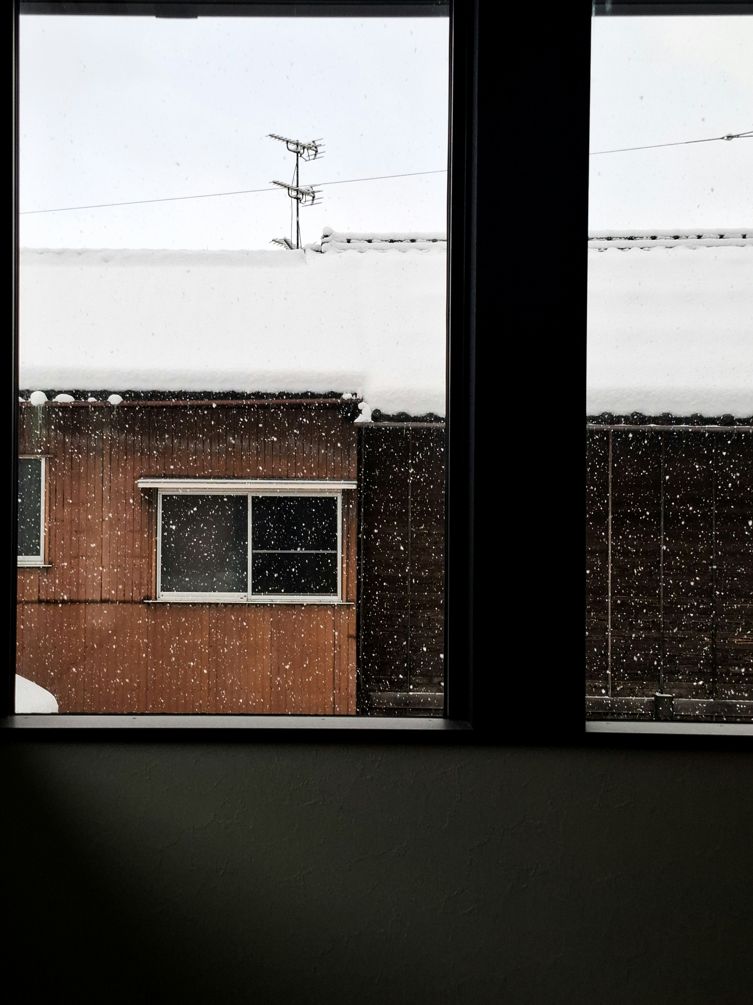 透过窗户看到下雪的砖房