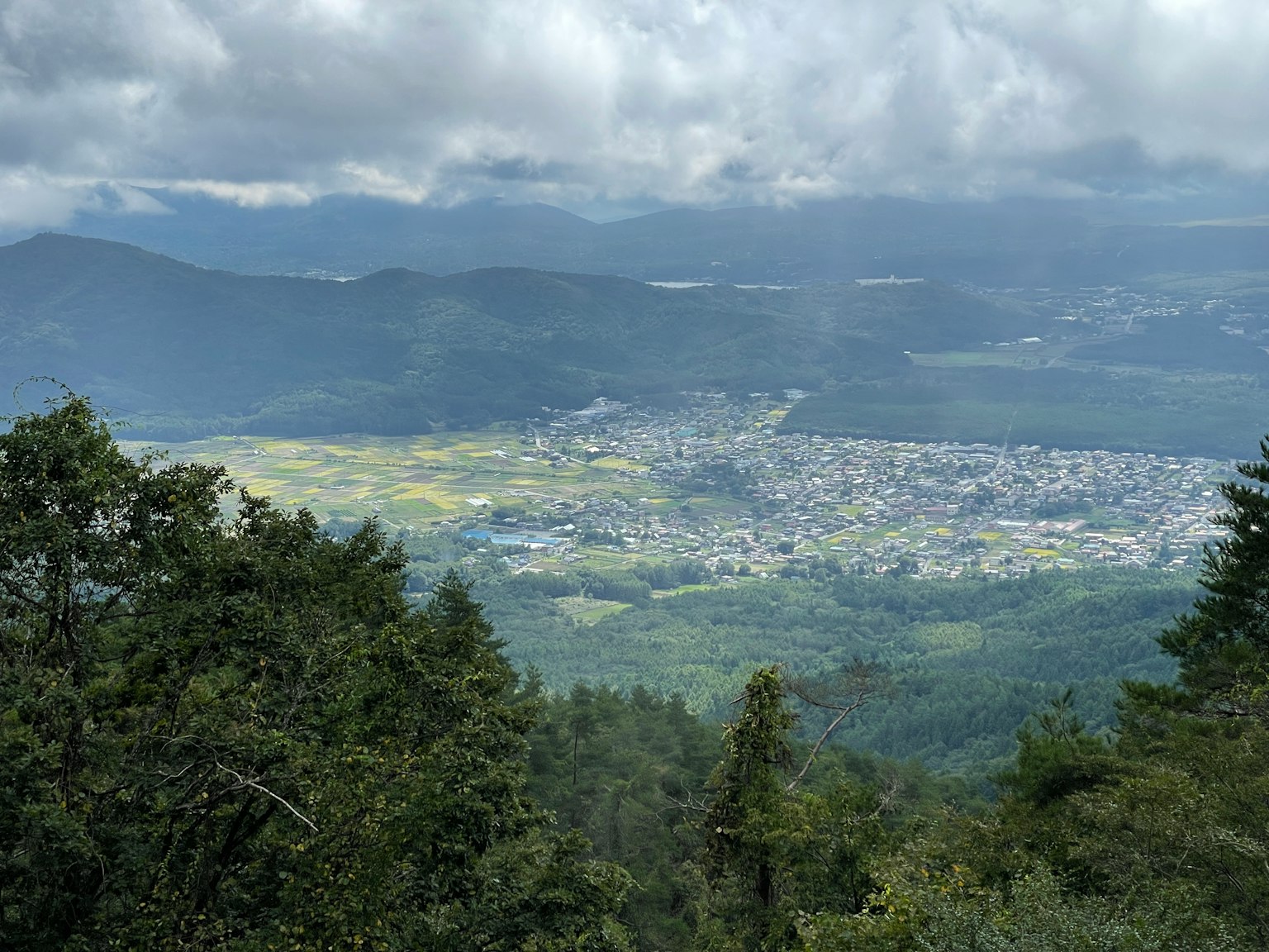 Pemandangan panorama lembah hijau dan sebuah kota kecil dari atas gunung