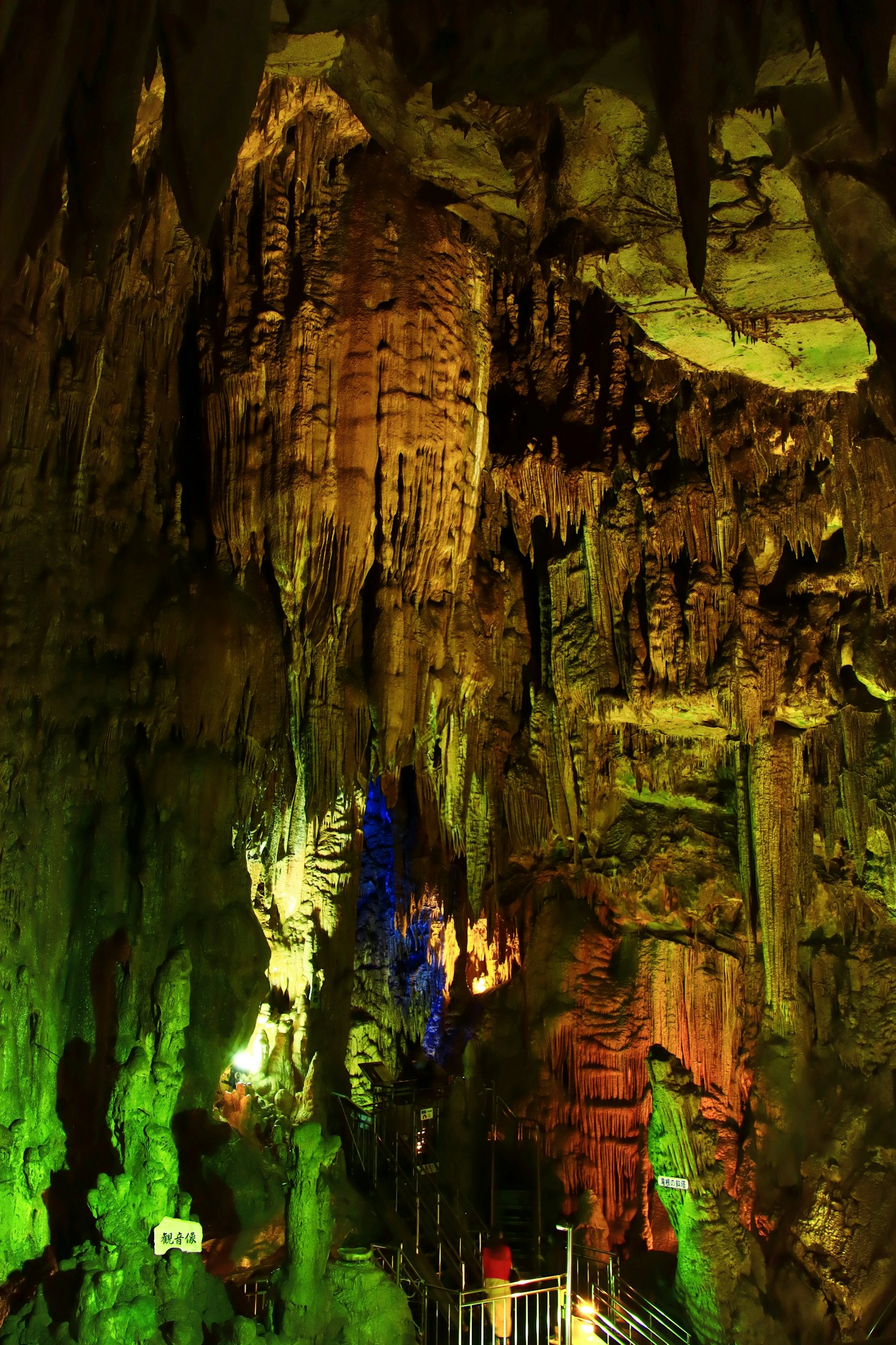 Interior of a cave illuminated with colorful lights showcasing stalactites and stalagmites