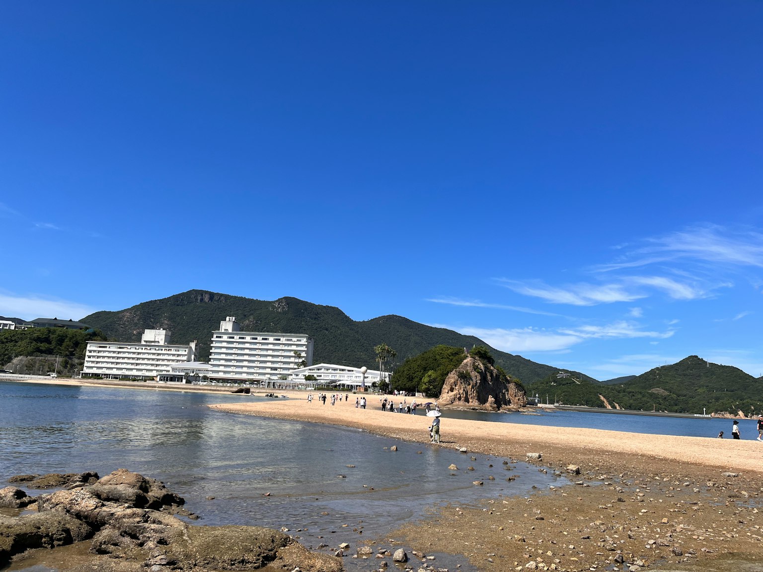 海灘場景，度假酒店在晴朗的藍天下和山脈之間
