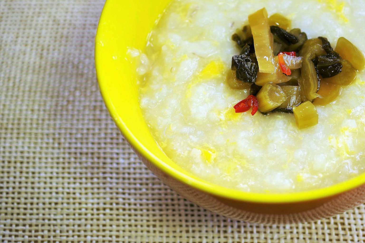 Porridge di riso in una ciotola gialla con verdure sott'aceto