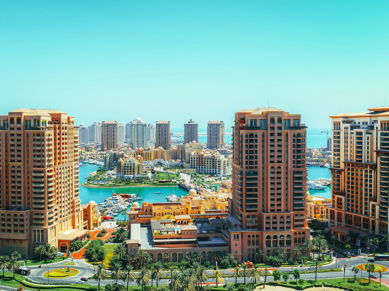 Cityscape featuring modern high-rise buildings and a marina under a blue sky