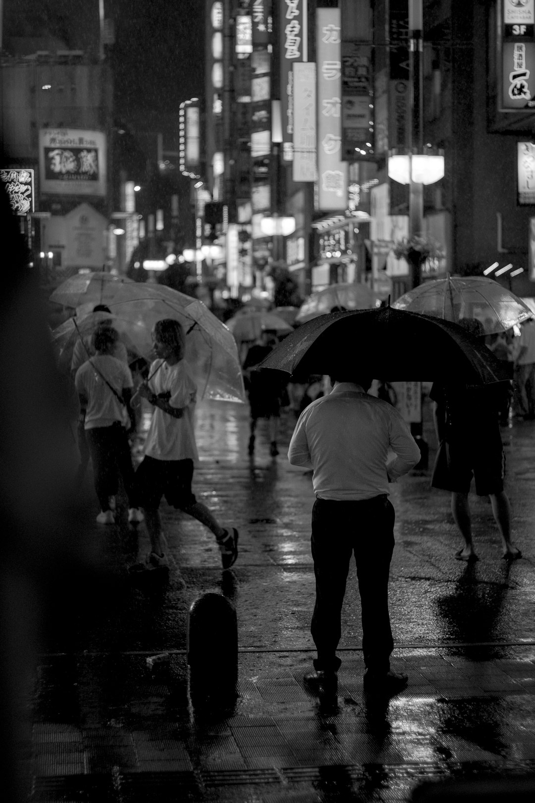 Des passants avec des parapluies sous la pluie, la nuit, dans une rue animée