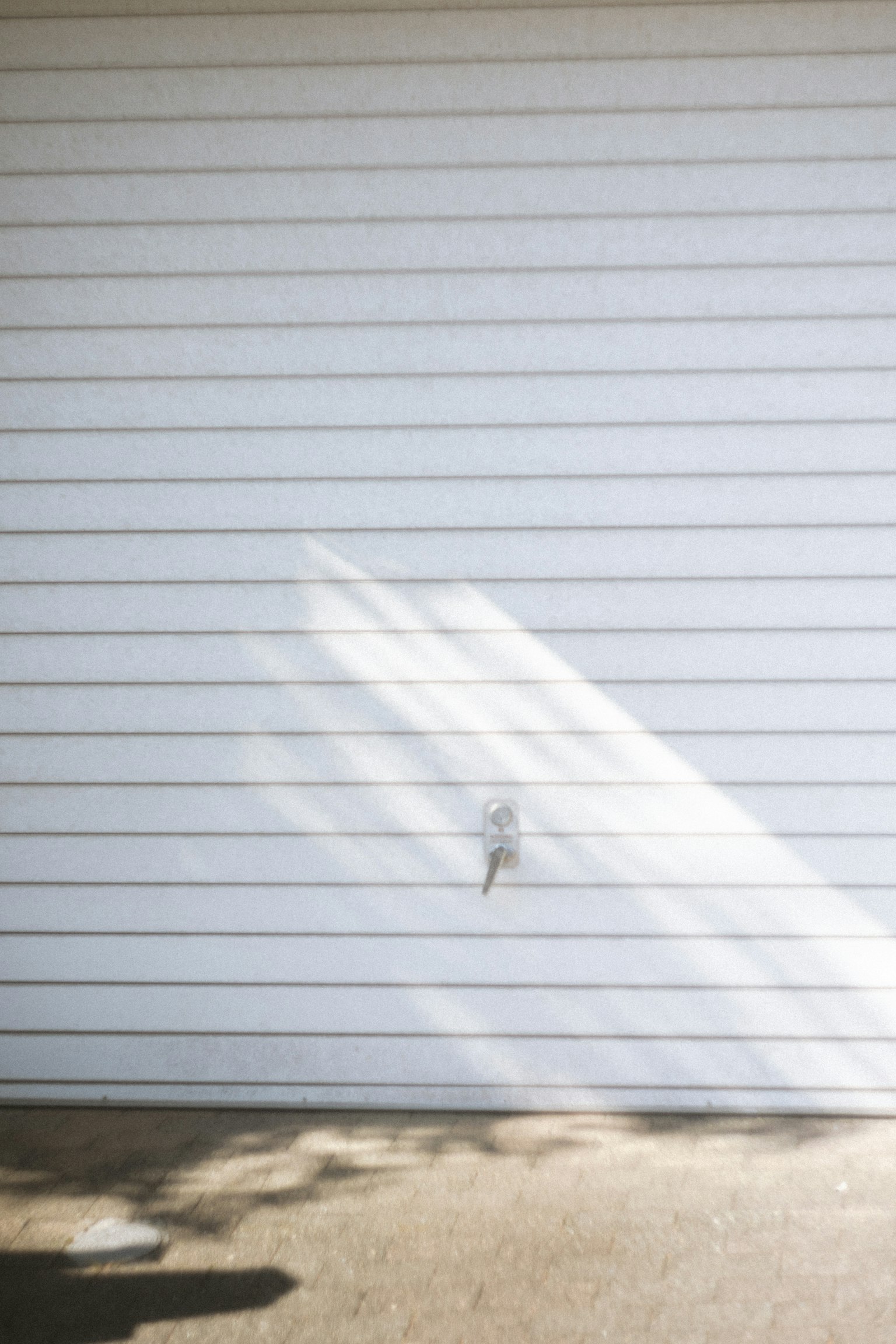 白いガレージのドアに影が映るシンプルな画像