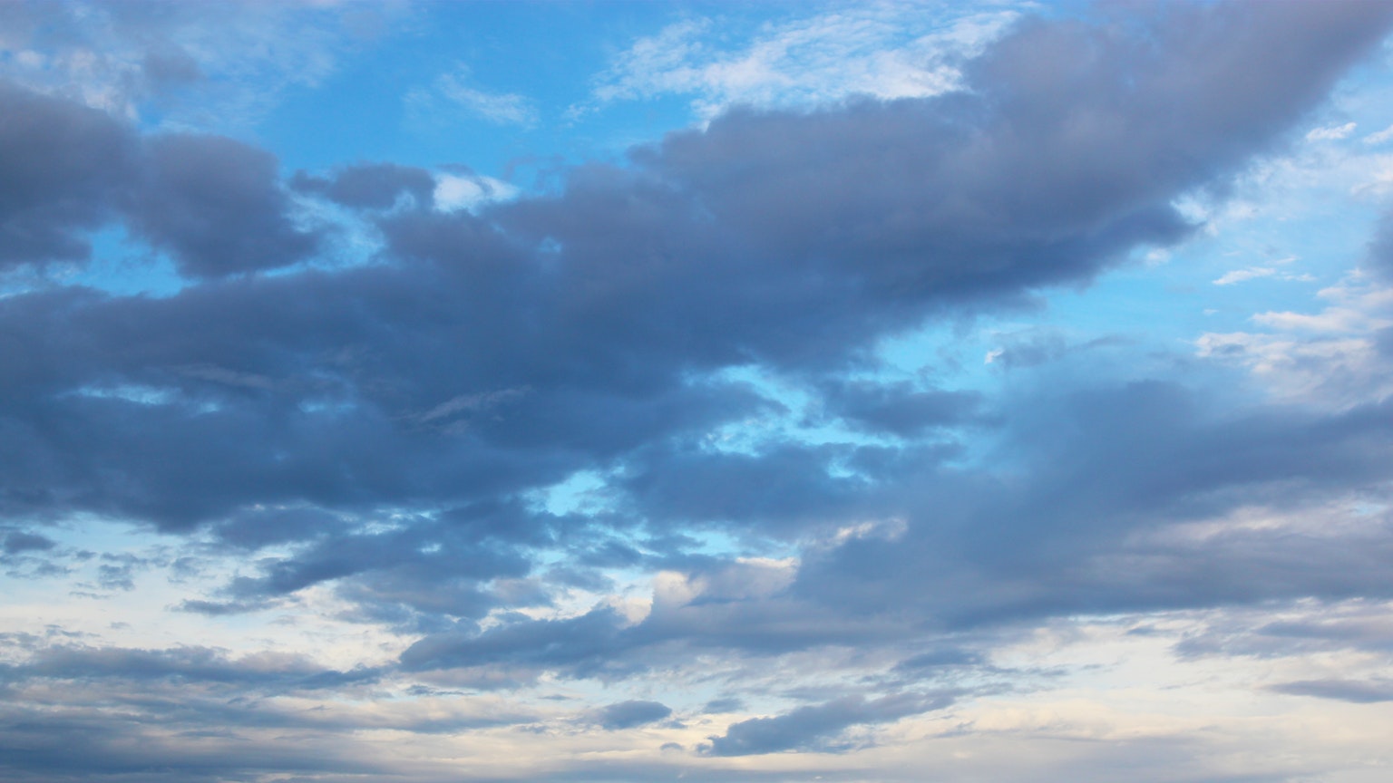 Un paesaggio di nuvole grigie che fluttuano in un cielo blu