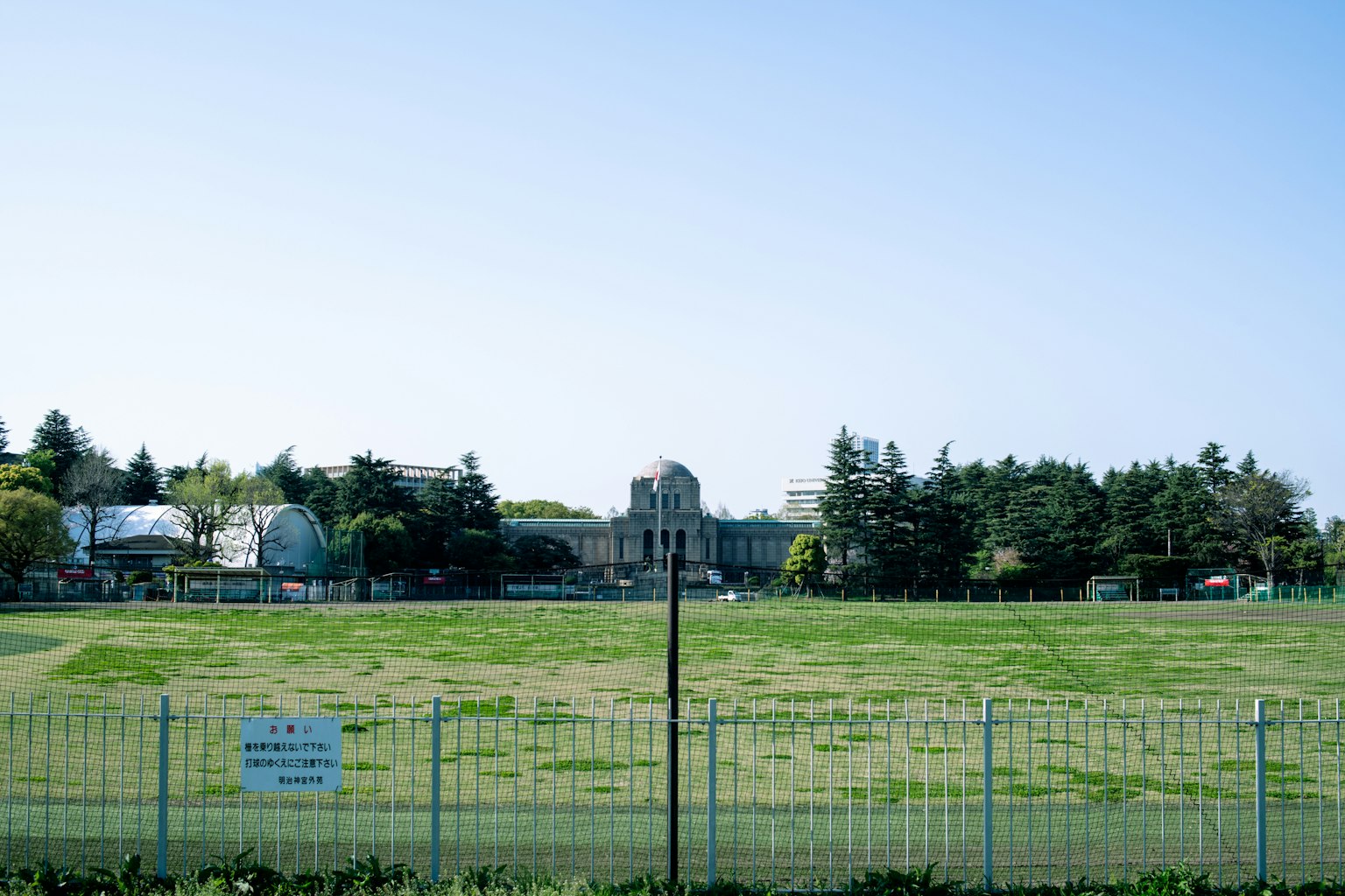 寬闊的綠色草坪與圍欄 背景有歷史建築和樹木