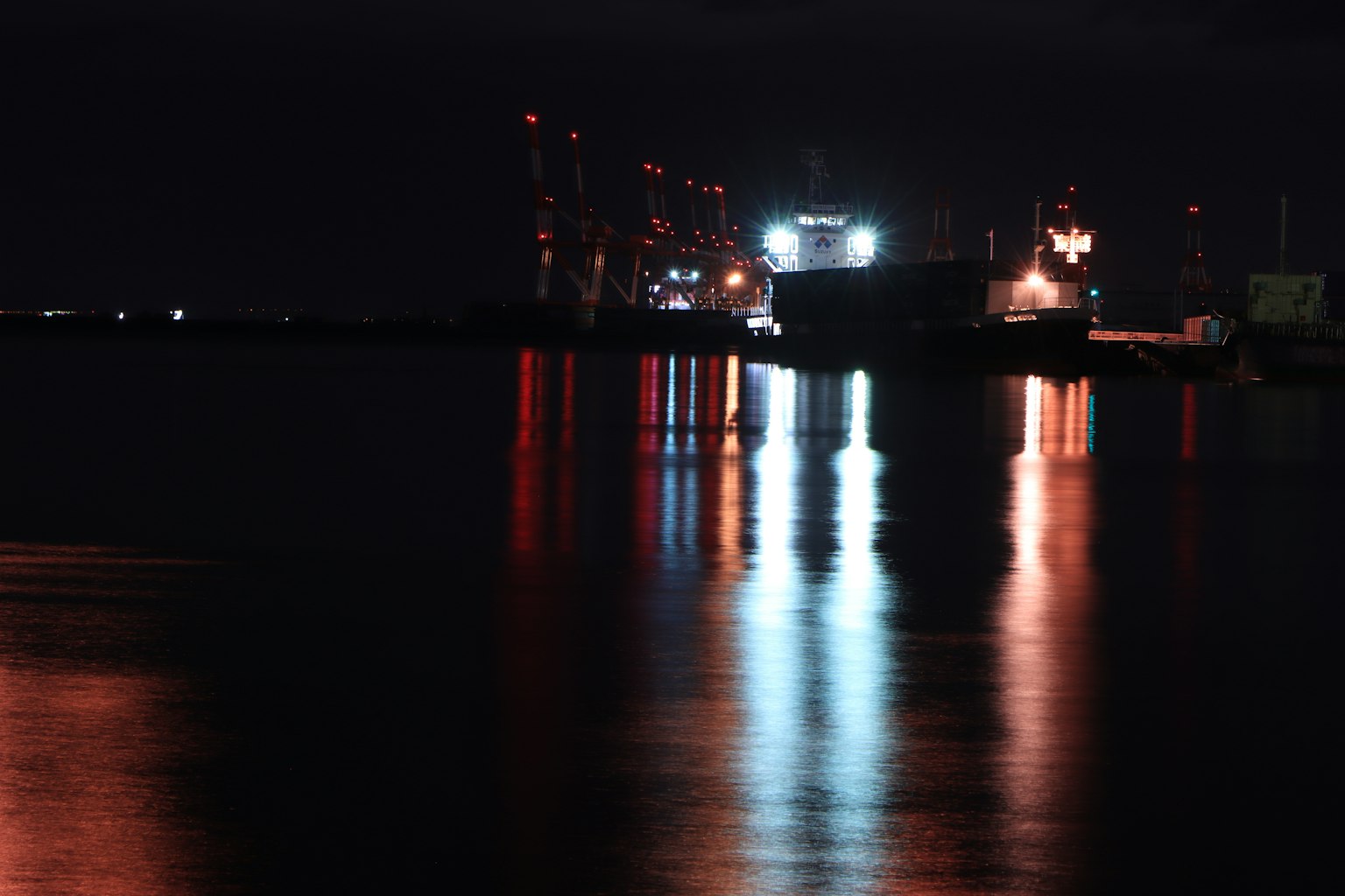 Lumières colorées se reflétant sur la surface de l'eau d'un port nocturne