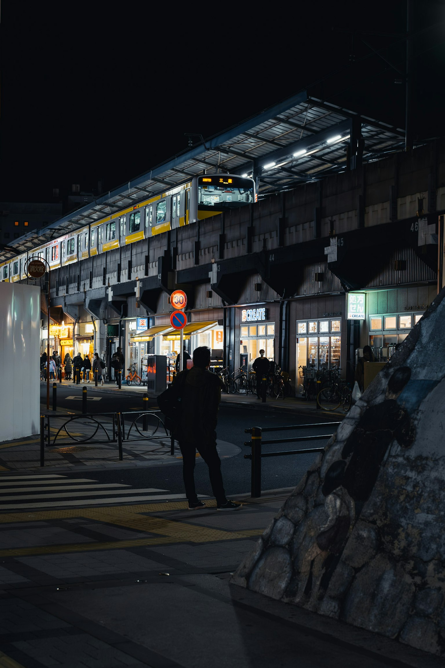 夜晚街道上站著的人和亮燈的商店在火車站附近