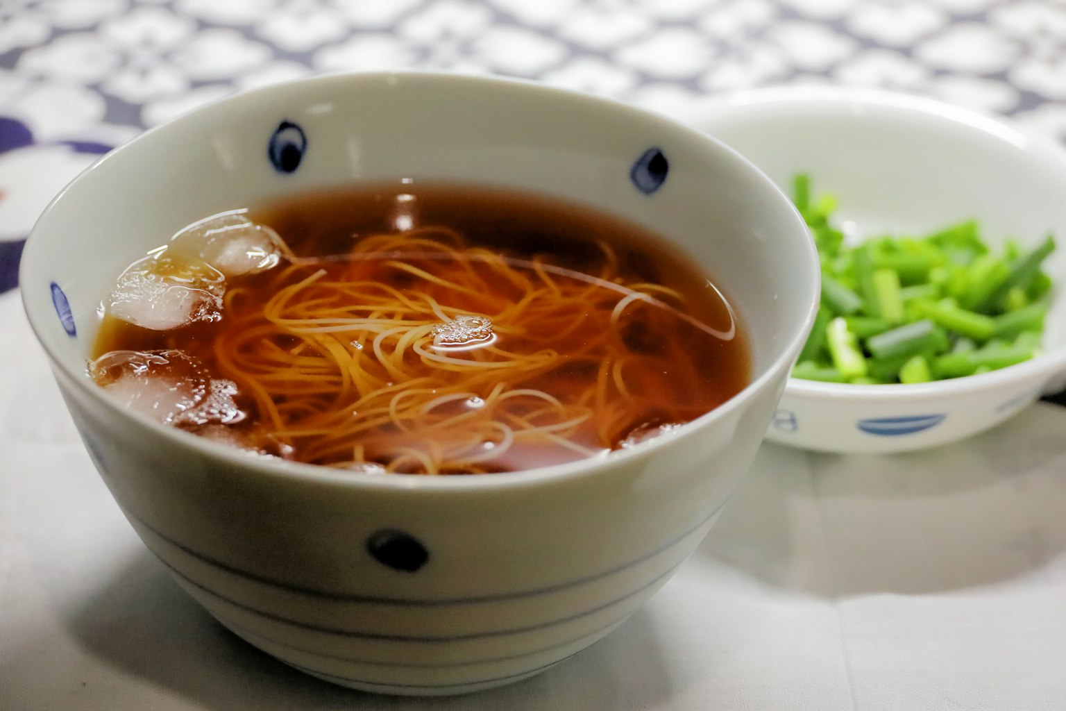 Bol de nouilles fines dans un bouillon avec un accompagnement d'oignons verts hachés