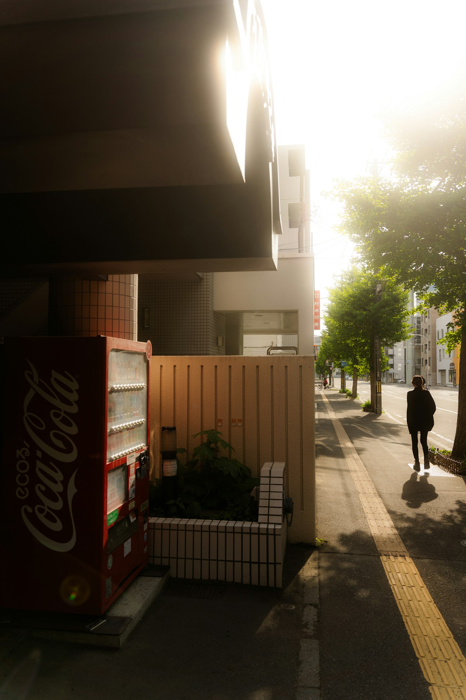 Scena di strada con un distributore Coca-Cola e luce solare