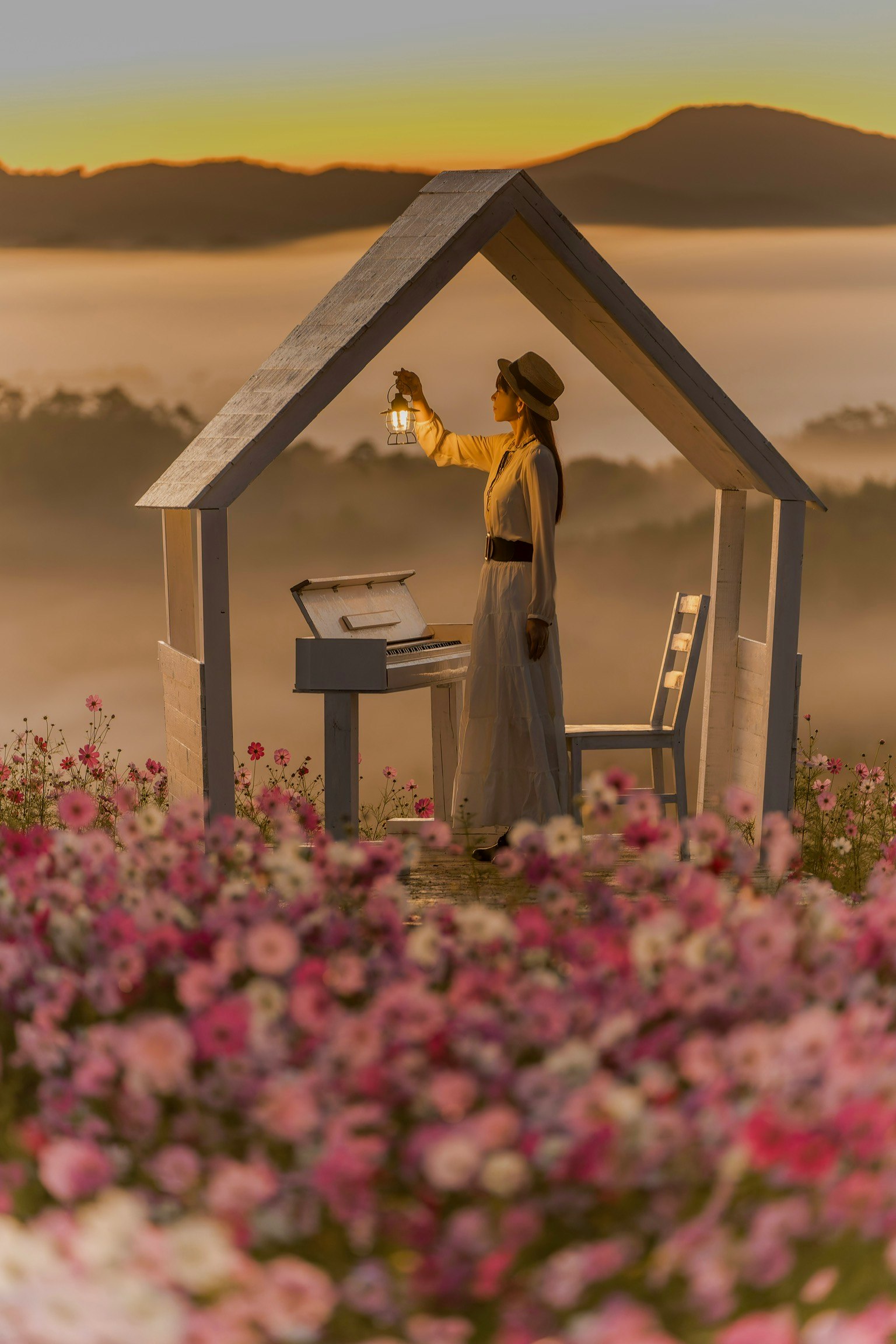 Une femme tenant une lanterne à l'intérieur d'une petite maison entourée de fleurs