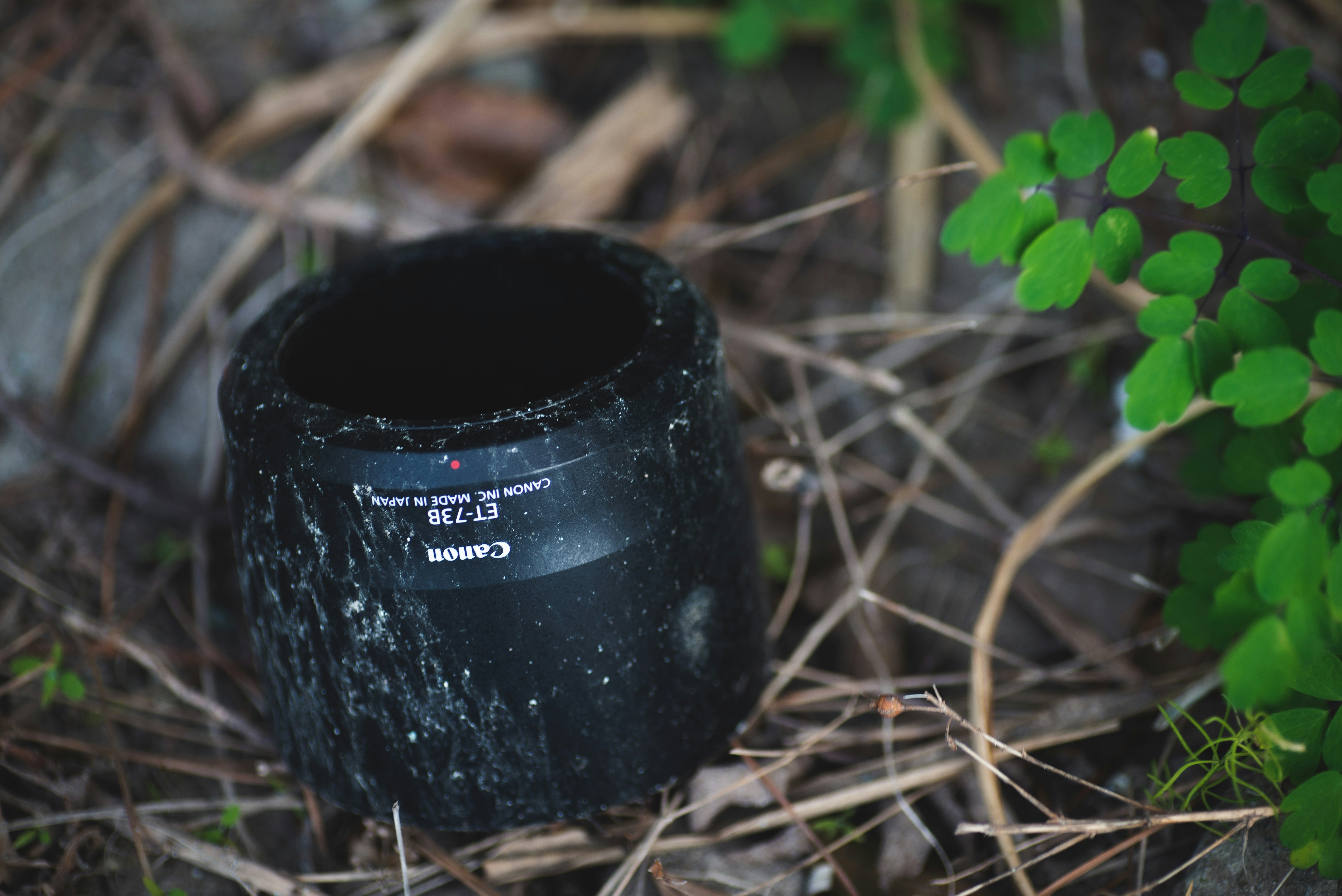 a black cylindrical lost-and-found item placed in grass