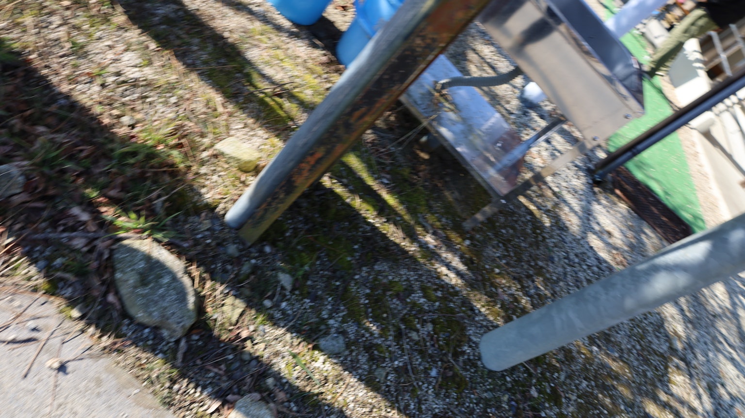 Scena all'aperto con contenitori blu e strutture metalliche a terra