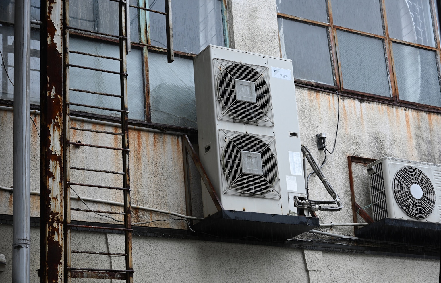 安裝在老建築外部的空調單元和生鏽的梯子