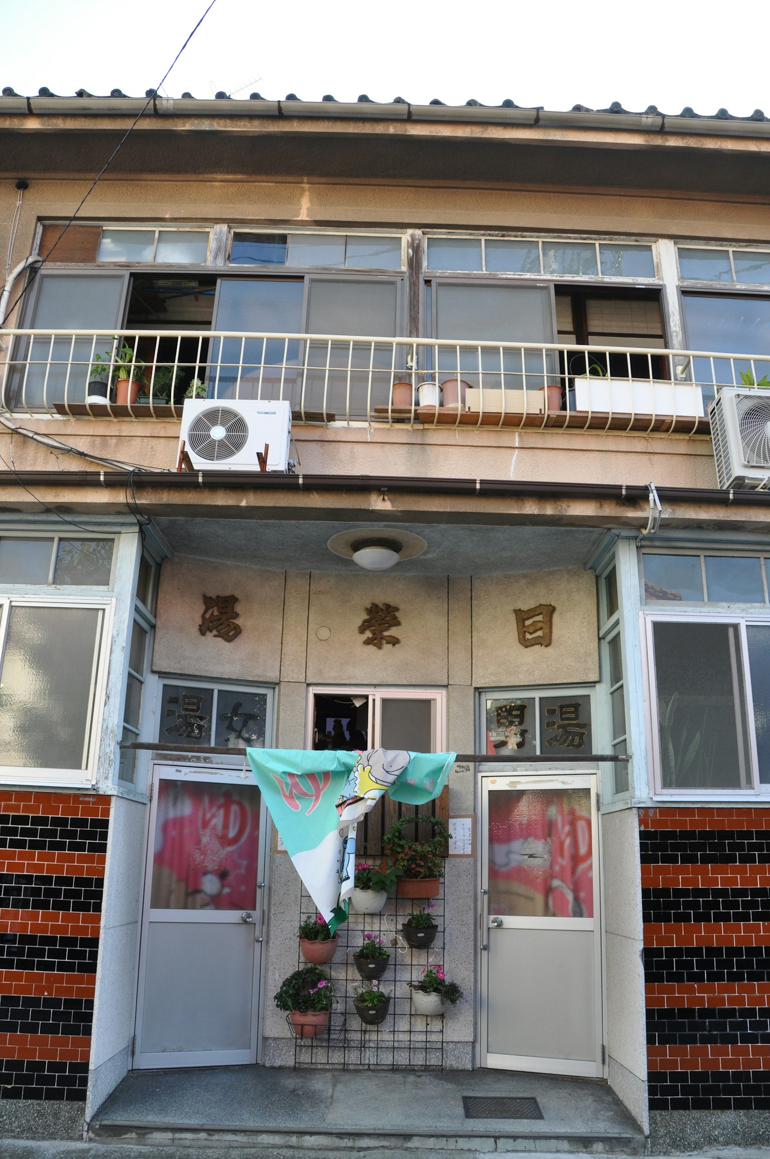 Extérieur d'un vieux bâtiment avec une unité de climatisation et un balcon, décorations à l'entrée
