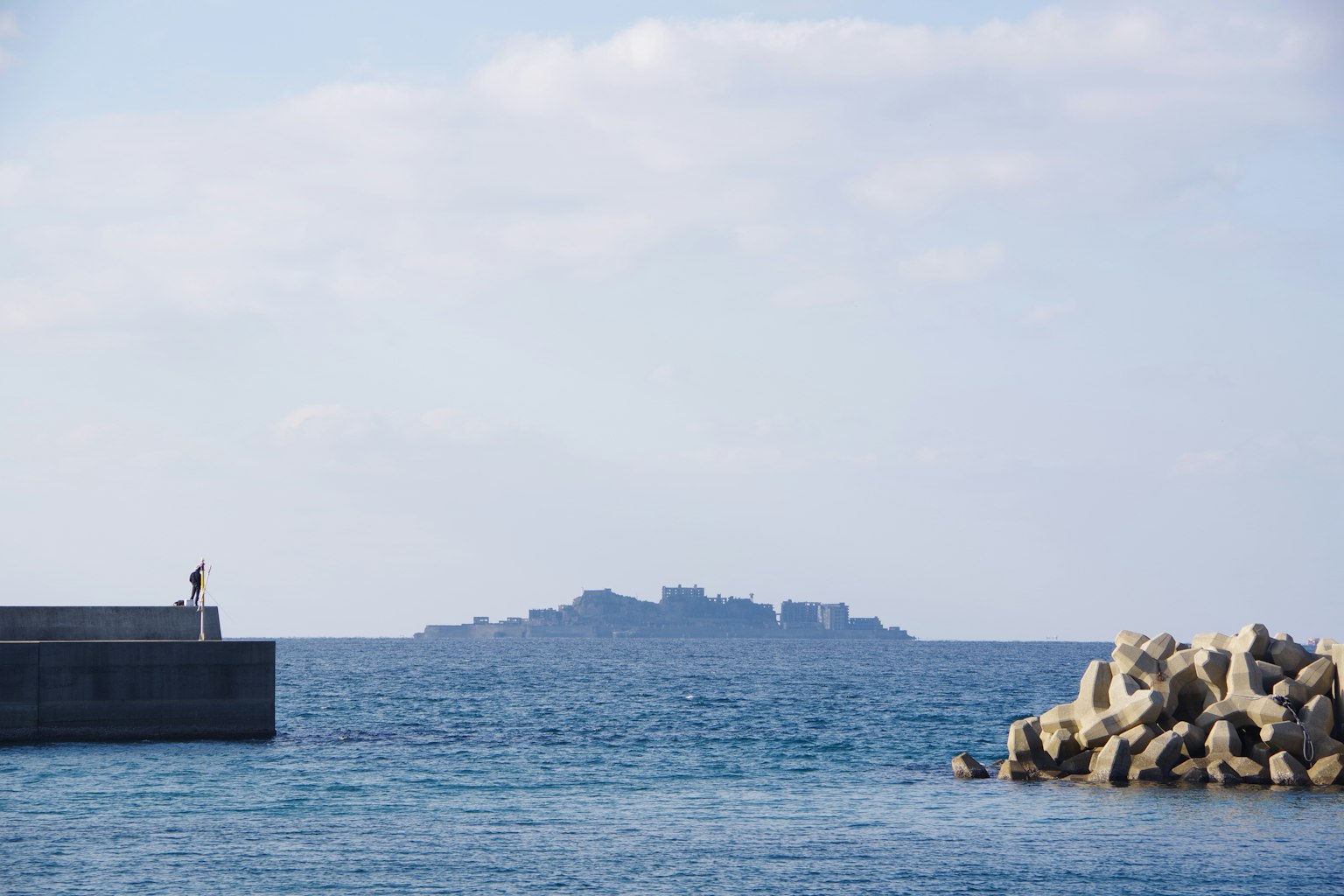 Paisaje marino con una persona en un muelle Isla visible al fondo