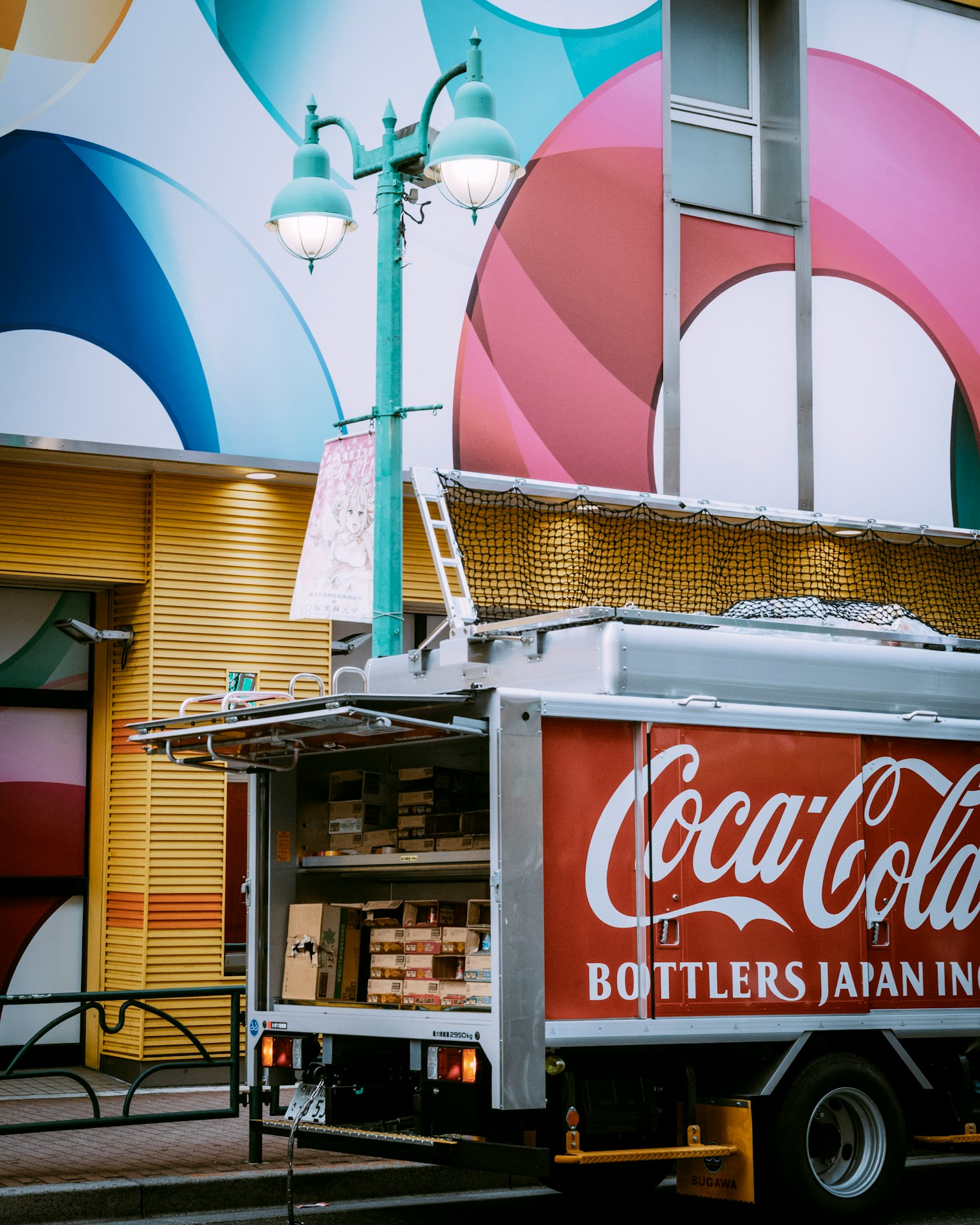 Truk Coca-Cola diparkir di depan dinding berwarna-warni