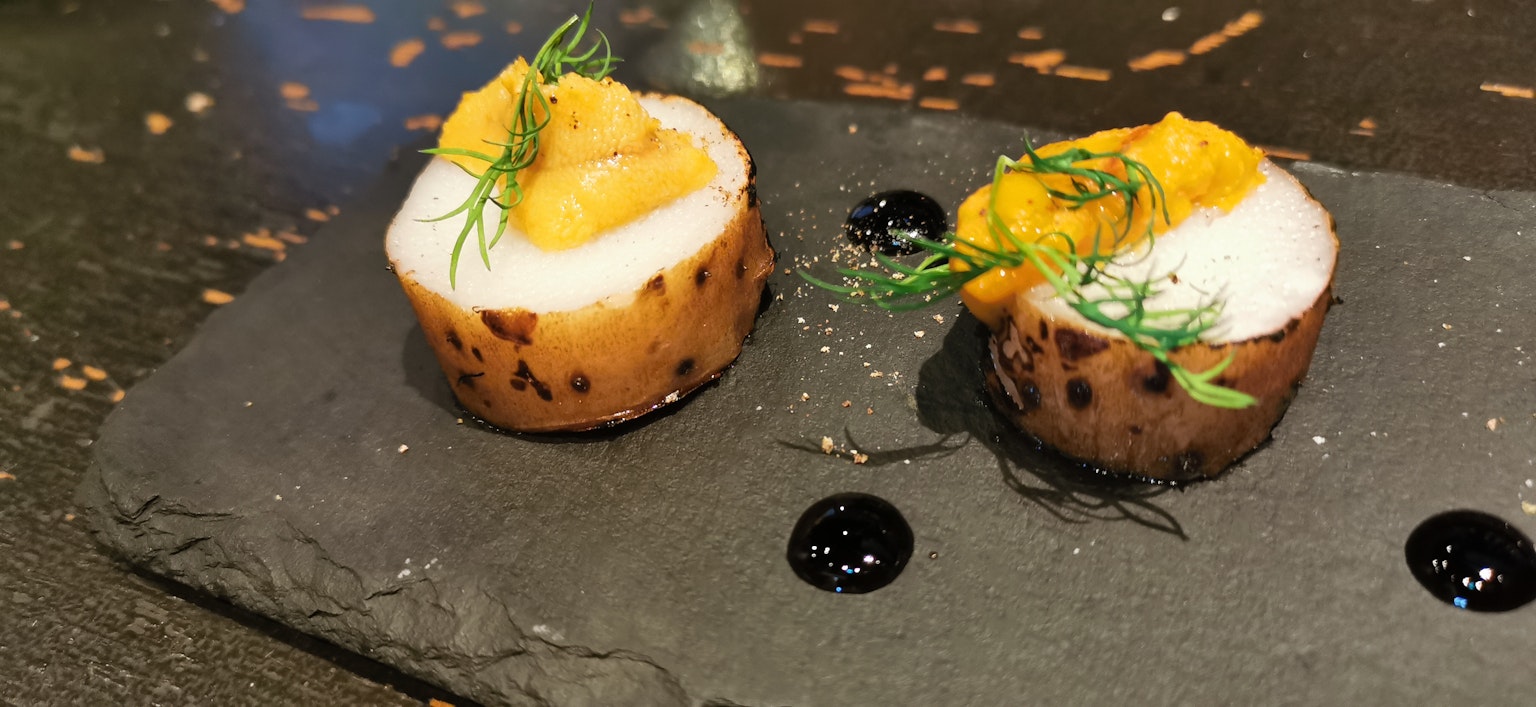 Due piatti simili a sushi presentati su un piatto di pietra nera