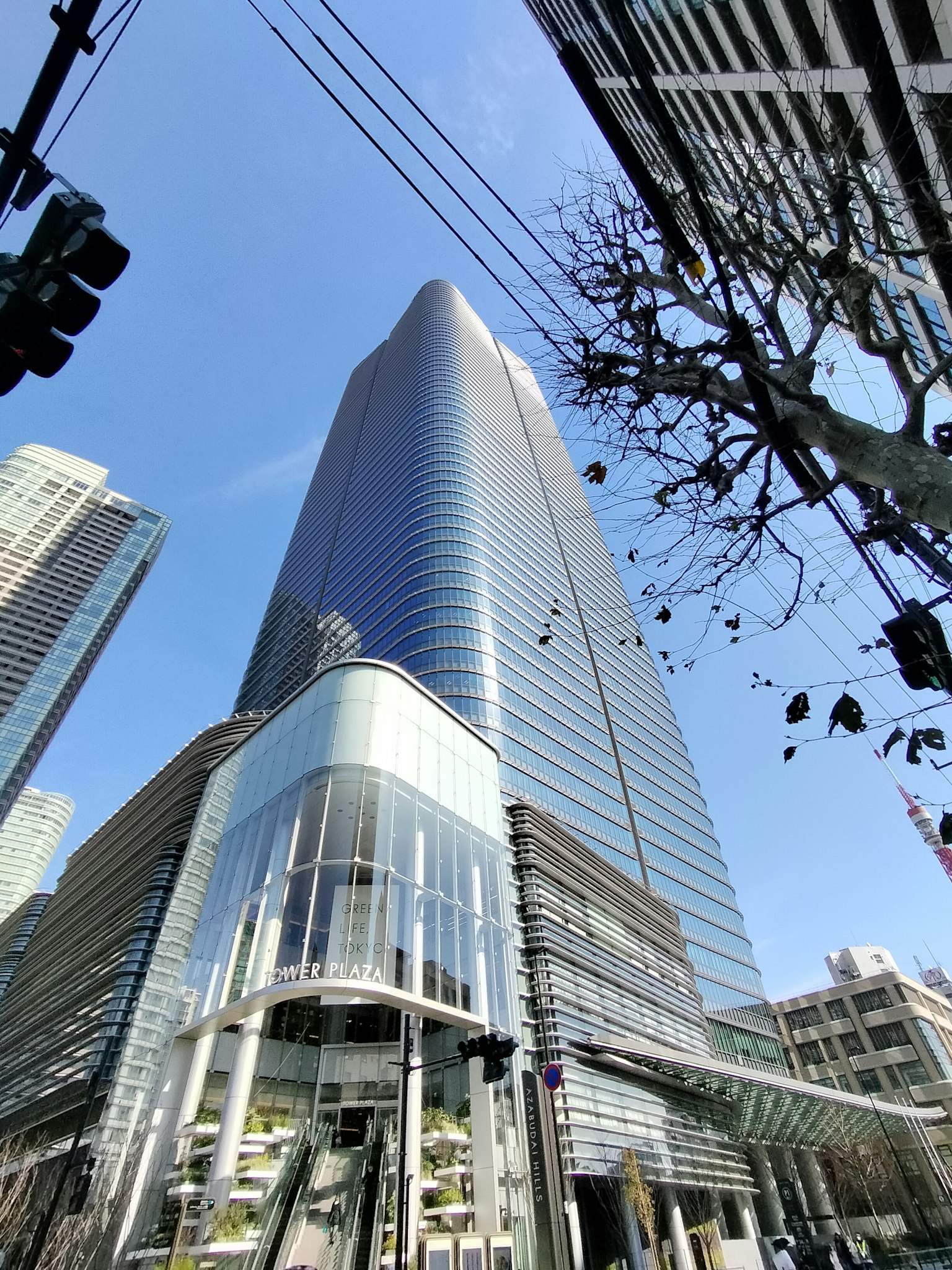 Pemandangan gedung pencakar langit dari bawah dengan langit biru cerah dan lingkungan perkotaan