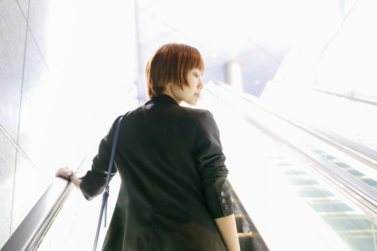 Une femme montant un escalator dans une lumière éclatante