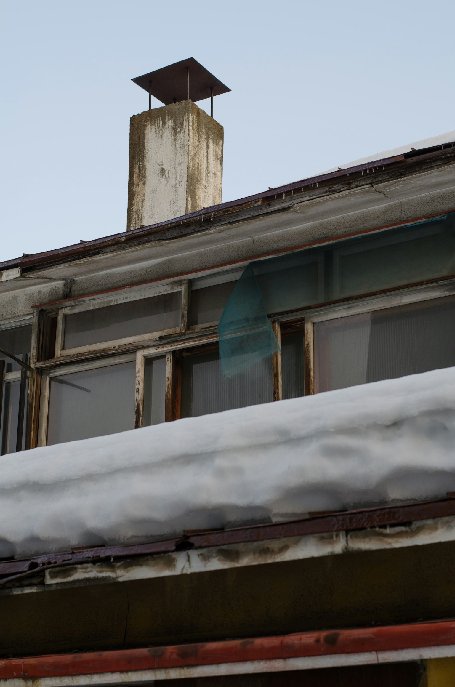 Partie d'un bâtiment avec un toit recouvert de neige et une vieille cheminée