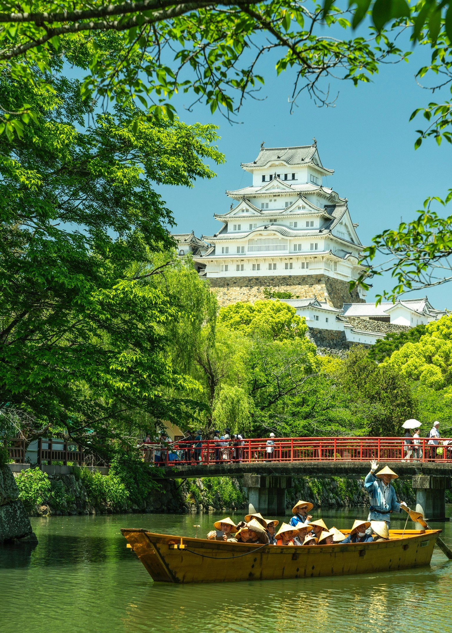 新緑の姫路城を川沿いの舟と緑の木々越しに望む景色