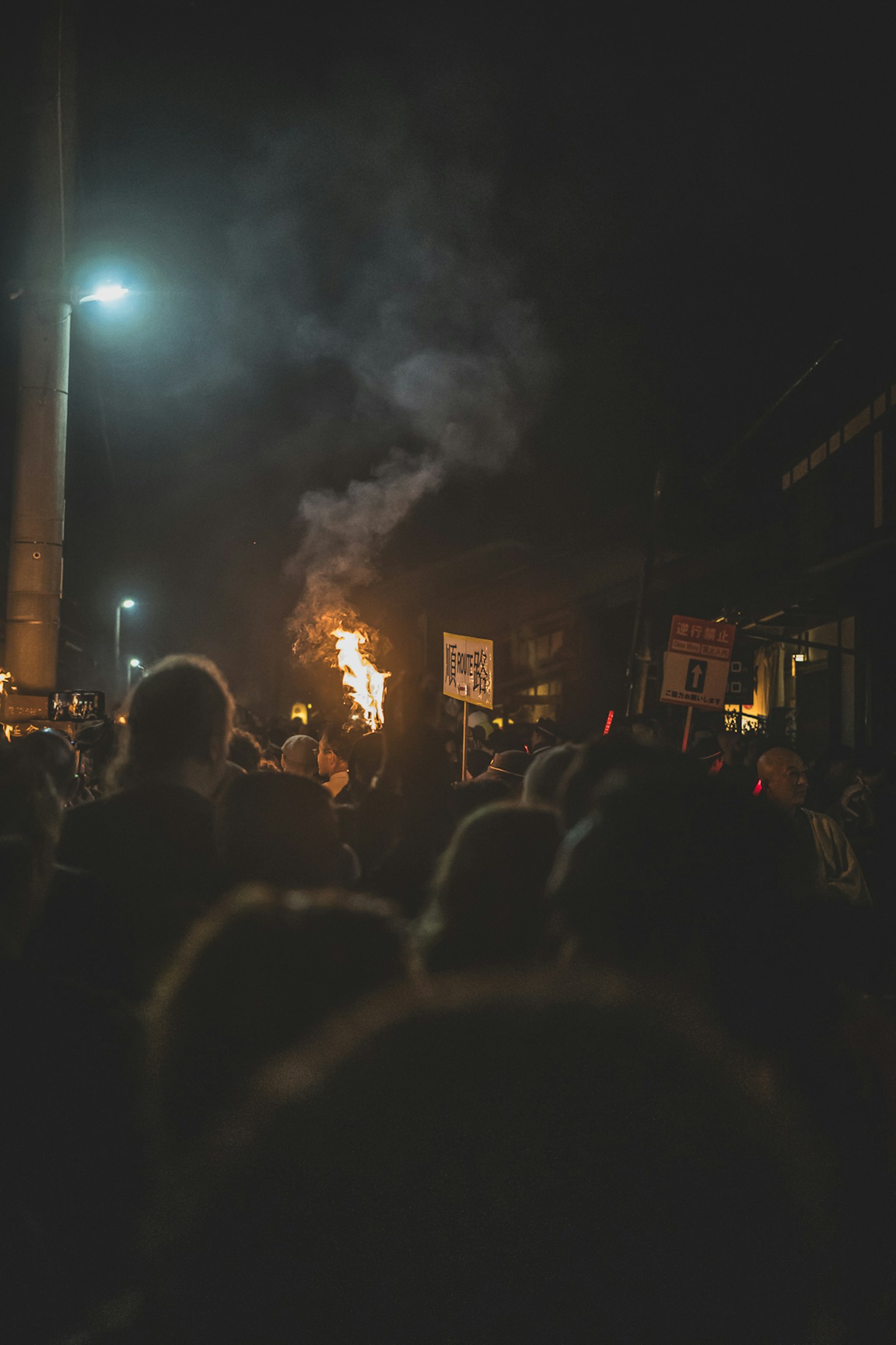 Multitud en una reunión nocturna con llamas y humo