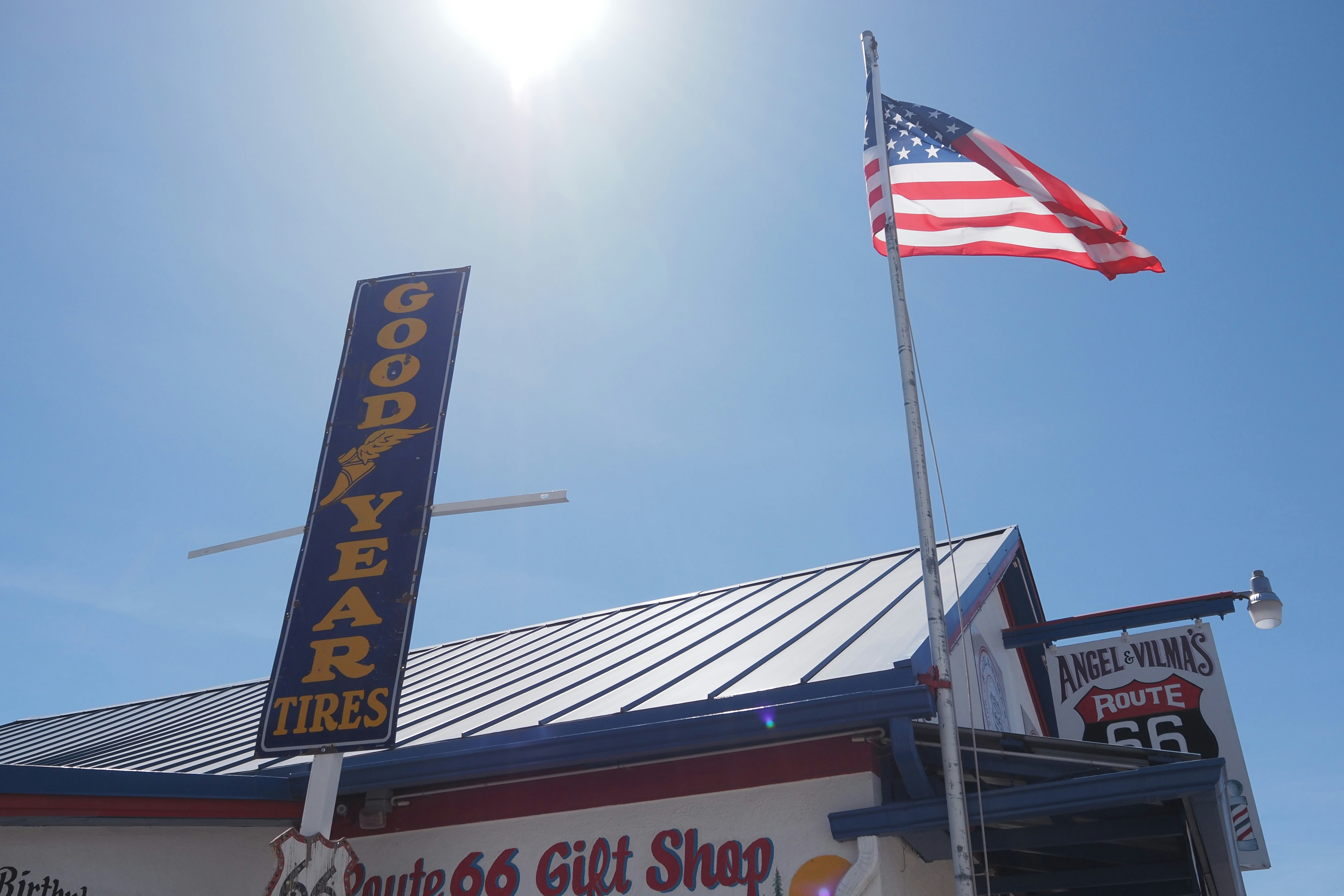 青空の下に立つ「Route 66」ギフトショップの看板と国旗