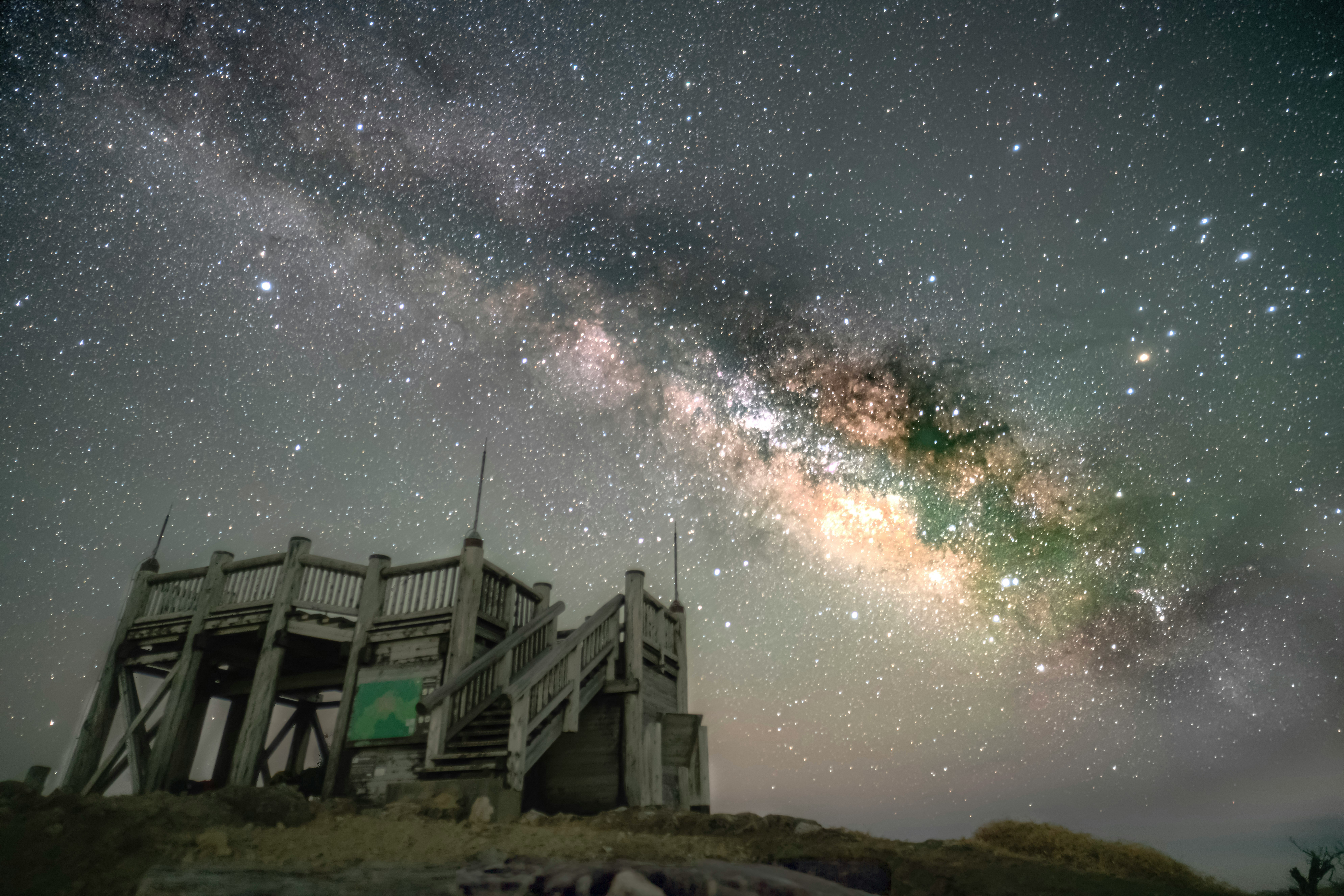 星空の下にある木製の展望台と天の川の美しい景色