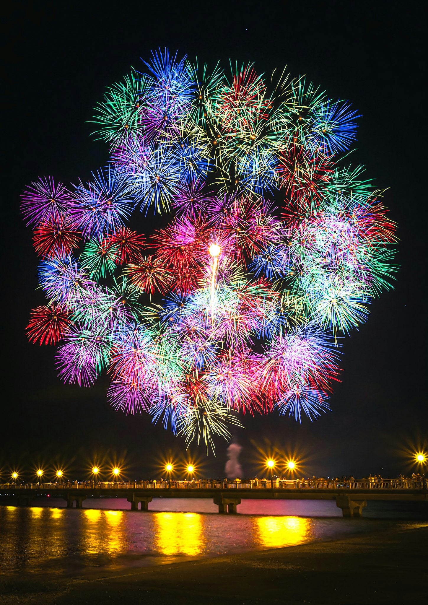 colorful fireworks blooming in the night sky with reflections on the water