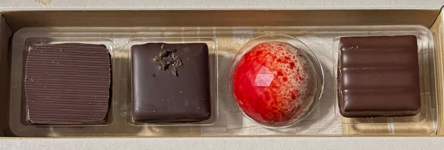 Une boîte contenant quatre chocolats différents disposés de manière ordonnée