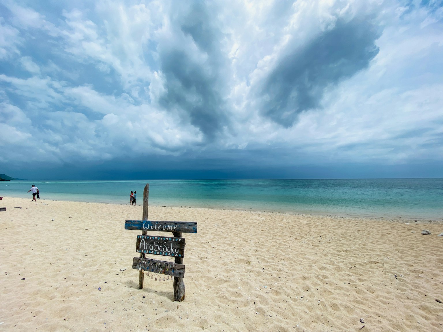 海灘風景，有一個標誌和戲劇性的雲彩在天空中