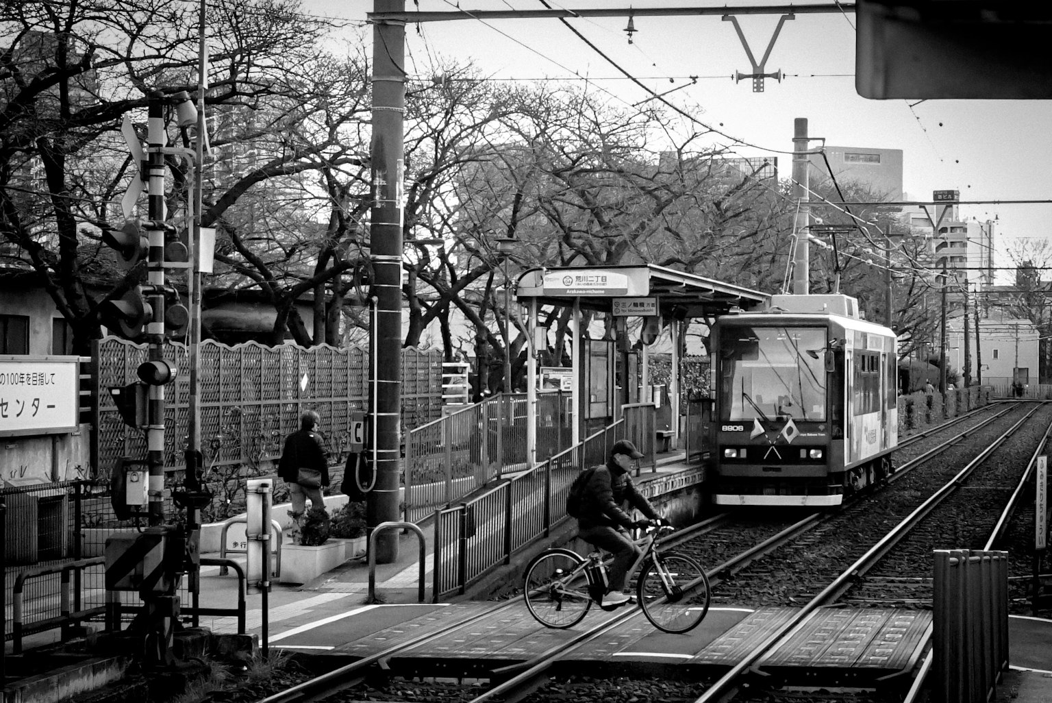 Black and white scene of a tram station with a bicycle and trees
