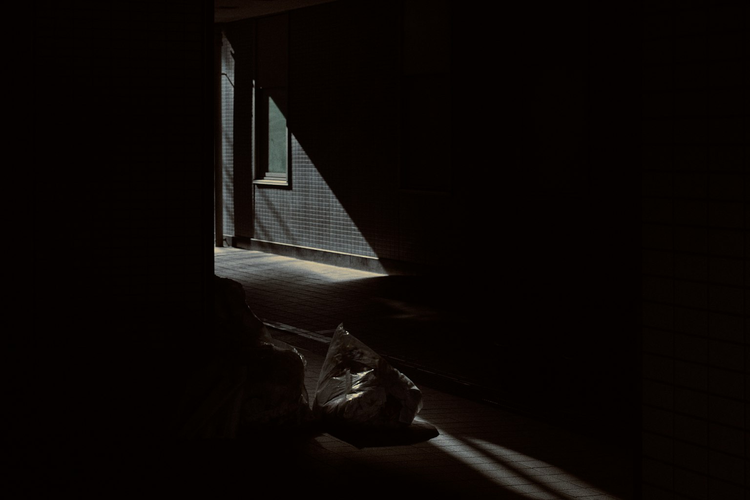 Couloir sombre avec de la lumière entrant et un sac en plastique sur le sol