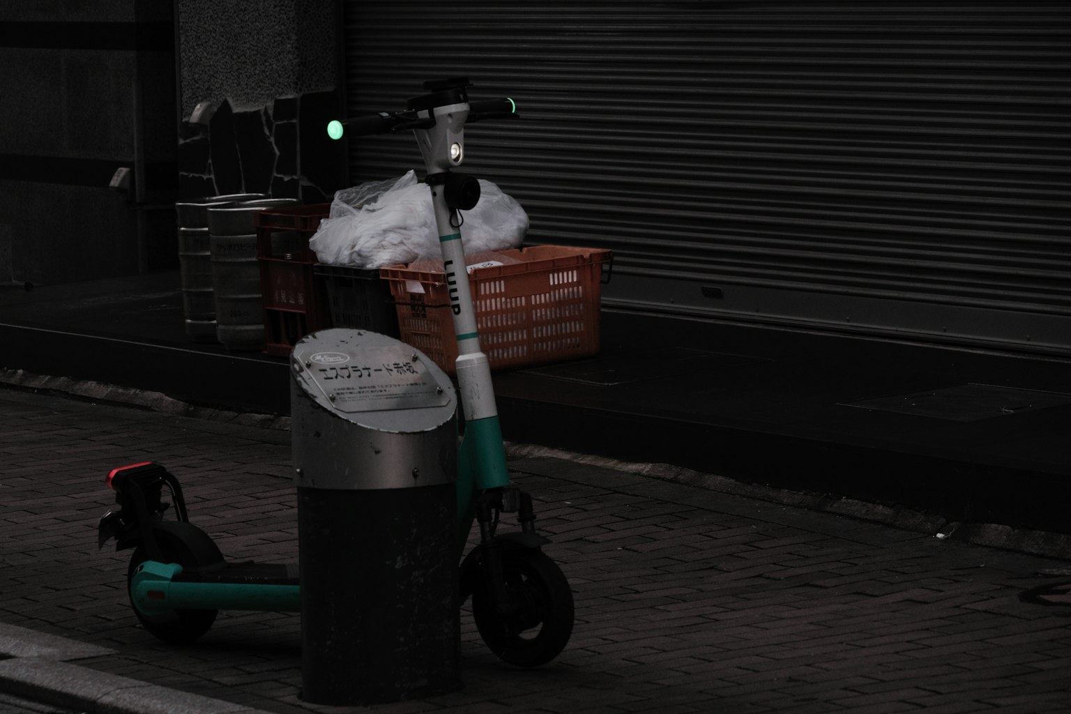 Trottinette électrique garée dans une rue sombre à côté d'une poubelle