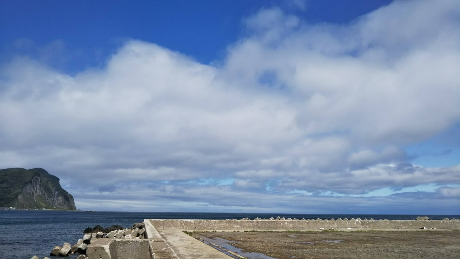 Coastal view with blue sky and white clouds Pier-like structure extending into the sea
