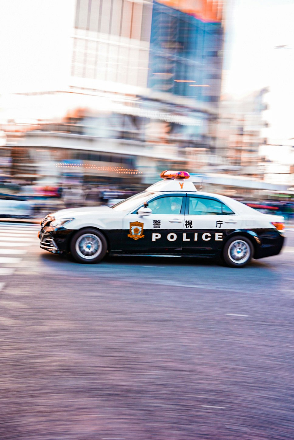 coche de policía con luces intermitentes circulando por una calle urbana