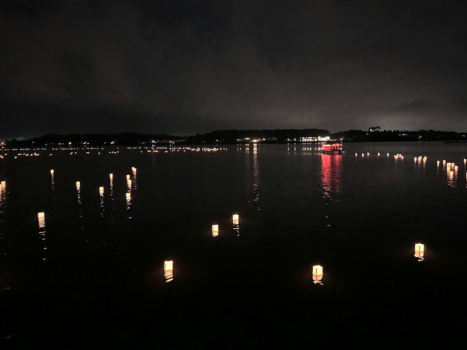 Scena notturna serena di lanterne galleggianti su un lago che riflettono la luce