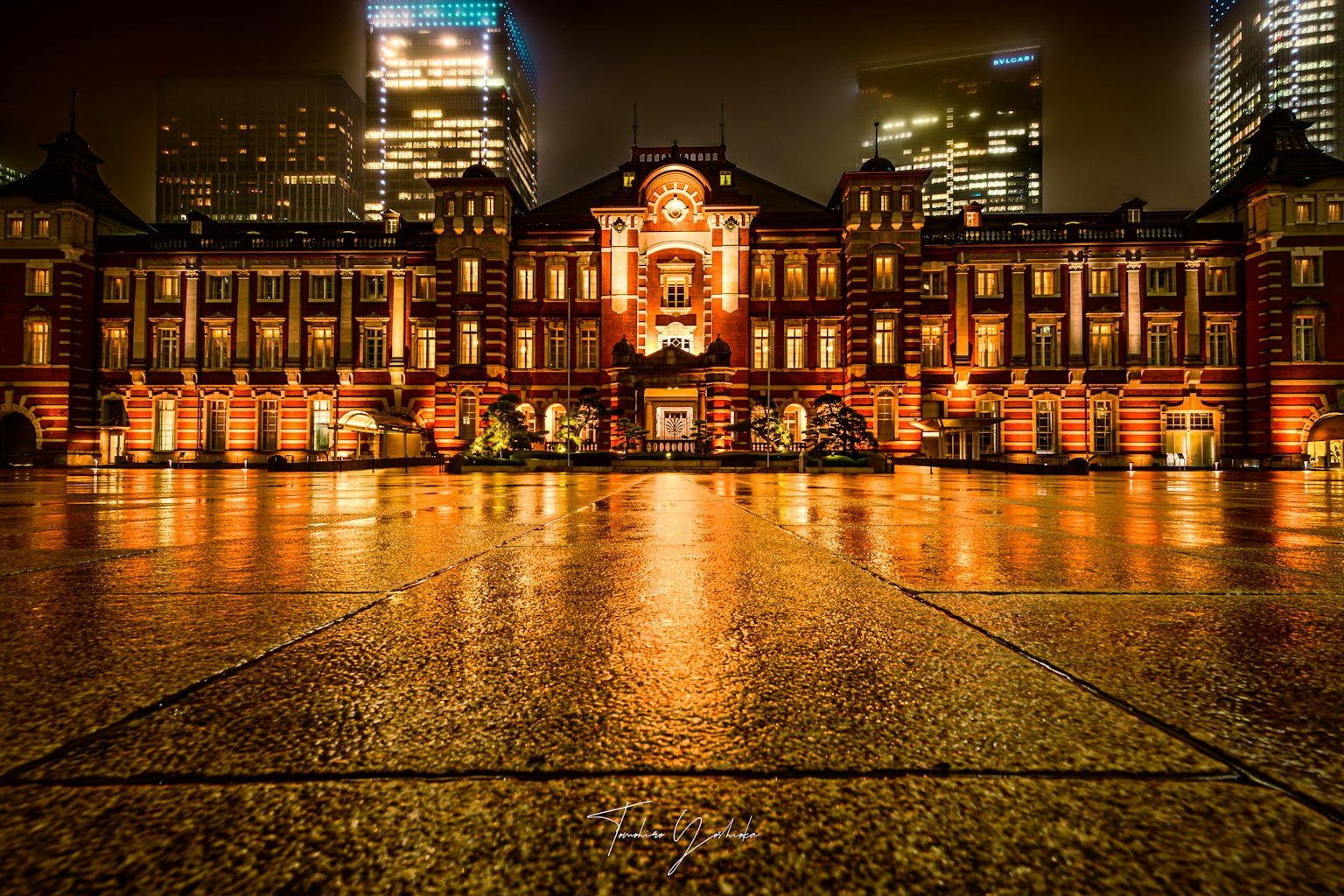 Gare de Tokyo la nuit avec des reflets sur le pavé mouillé