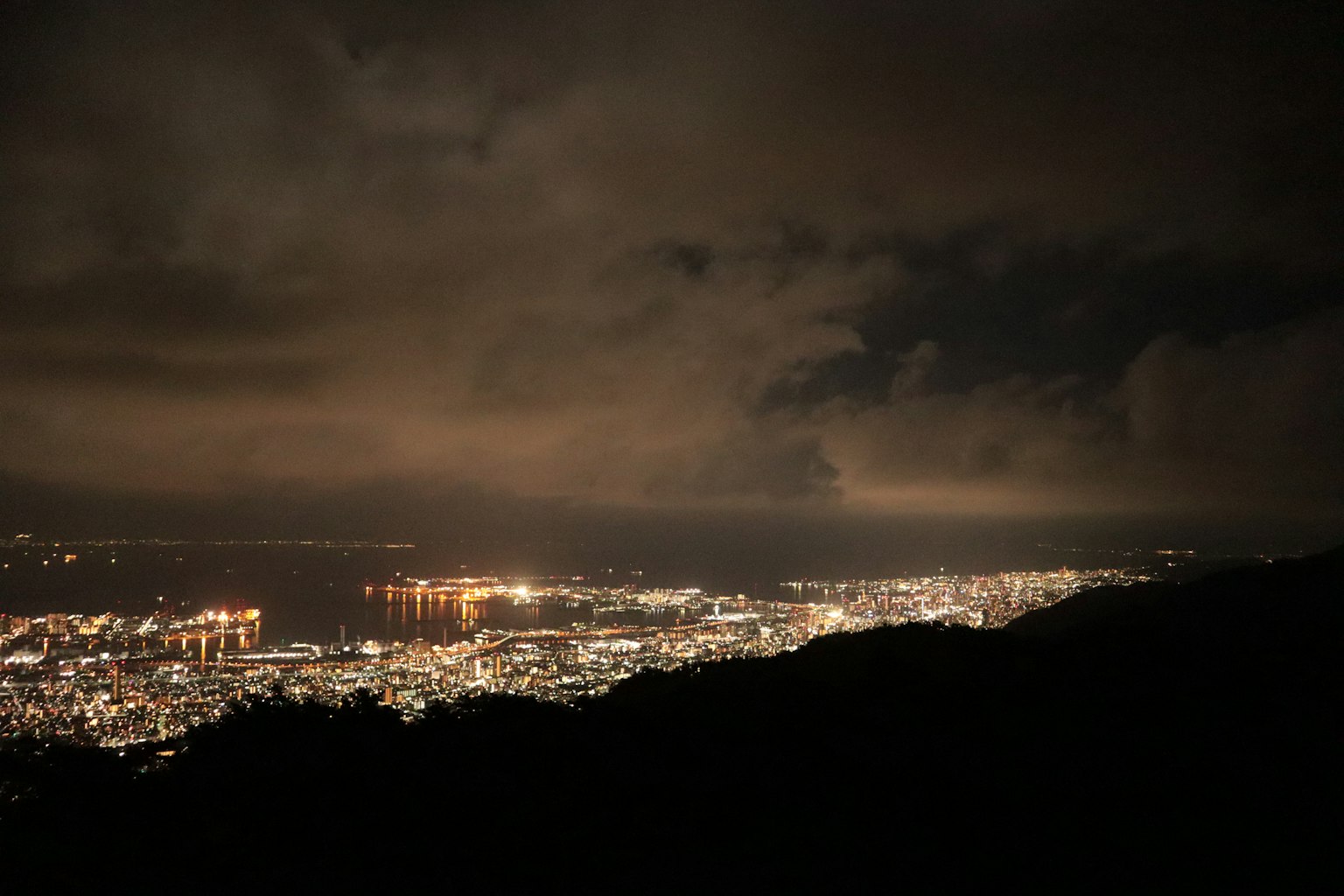 Pemandangan indah melihat kota di malam hari awan gelap dan lampu kota yang bersinar