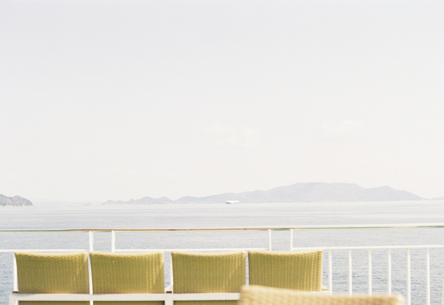 Una vista serena da un balcone con sedie giallo-verdi che si affacciano sull'oceano