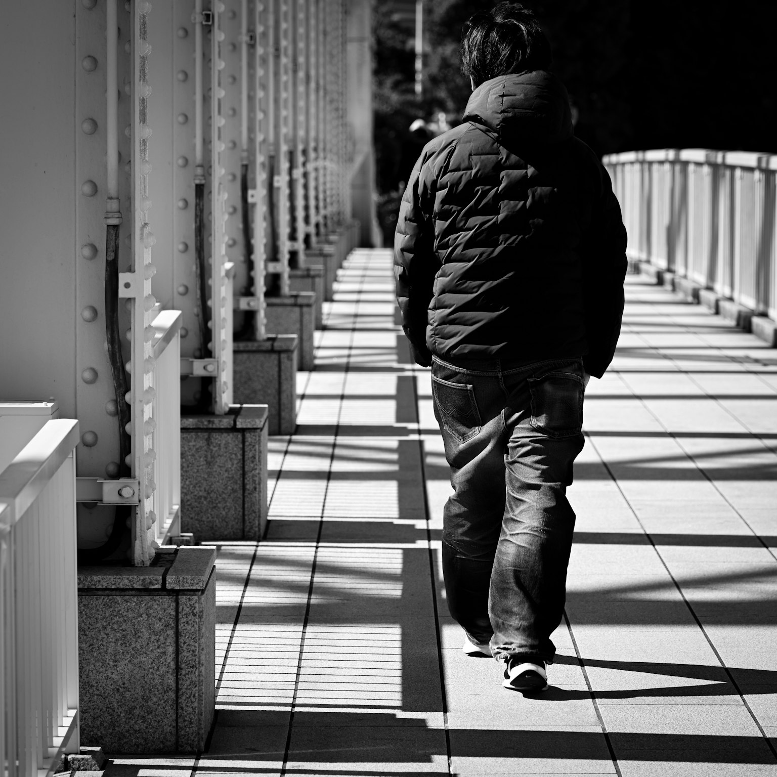 Ein Mann, der auf einer Brücke in einem Schwarzweißfoto geht
