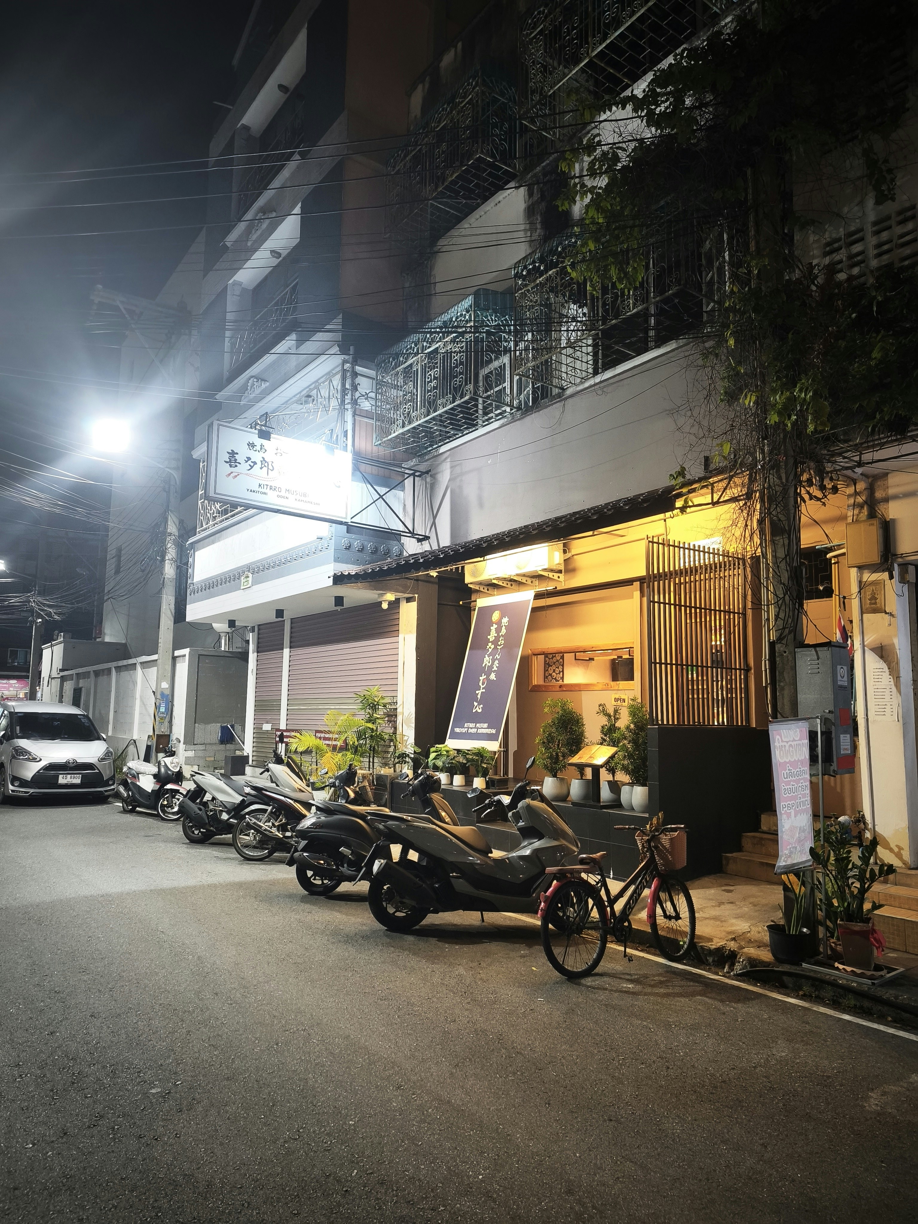 夜の路地に並ぶバイクと店先