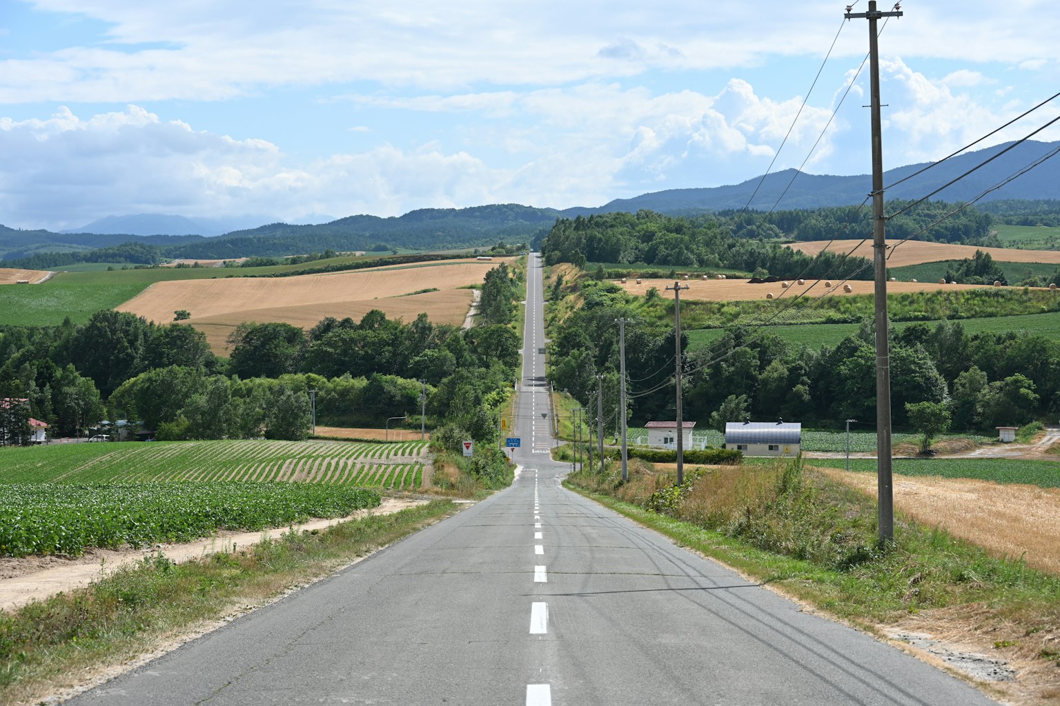 Gerade Straße, die durch eine ländliche Landschaft mit blauem Himmel führt