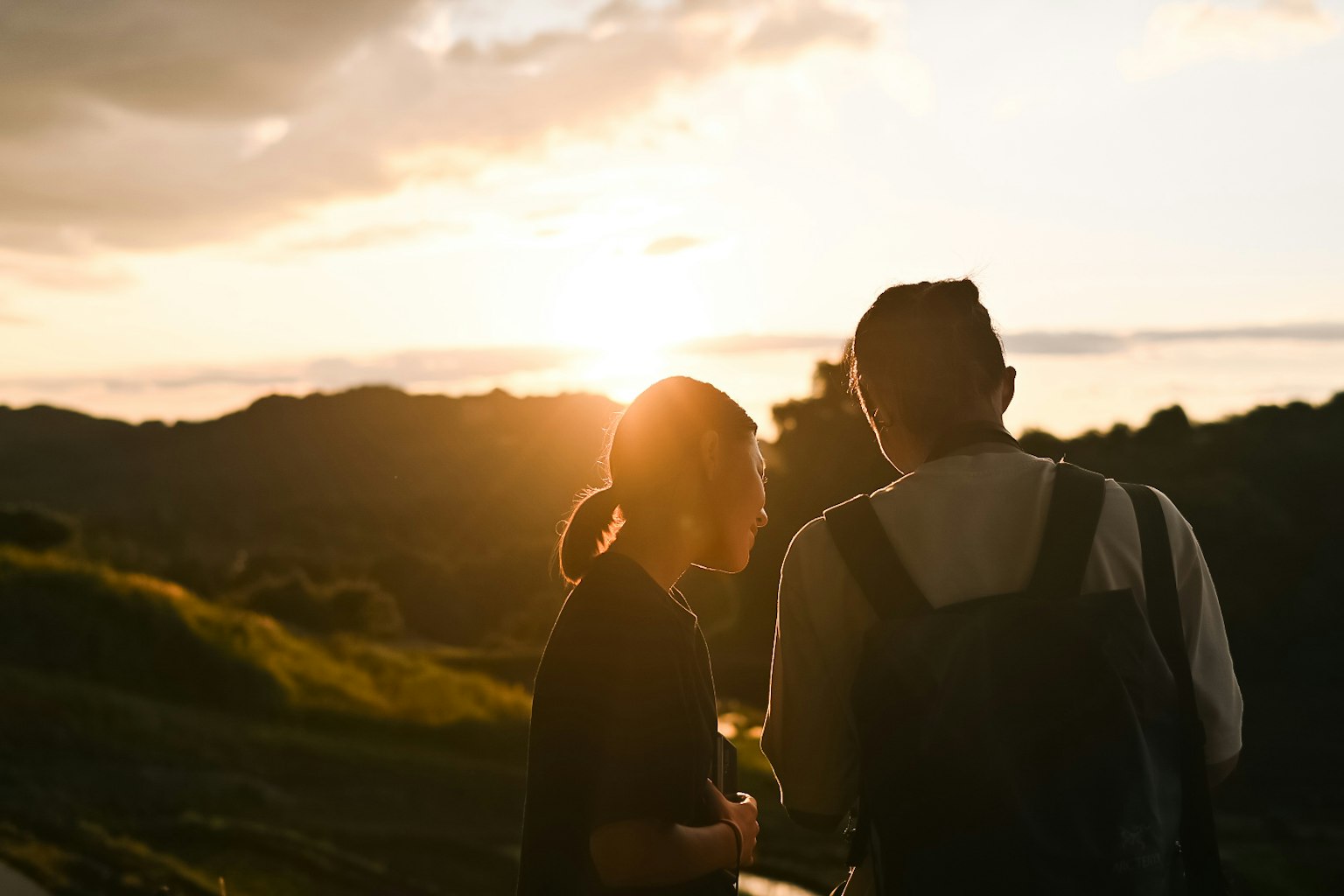 Zwei Personen im Gespräch vor einem Sonnenuntergang