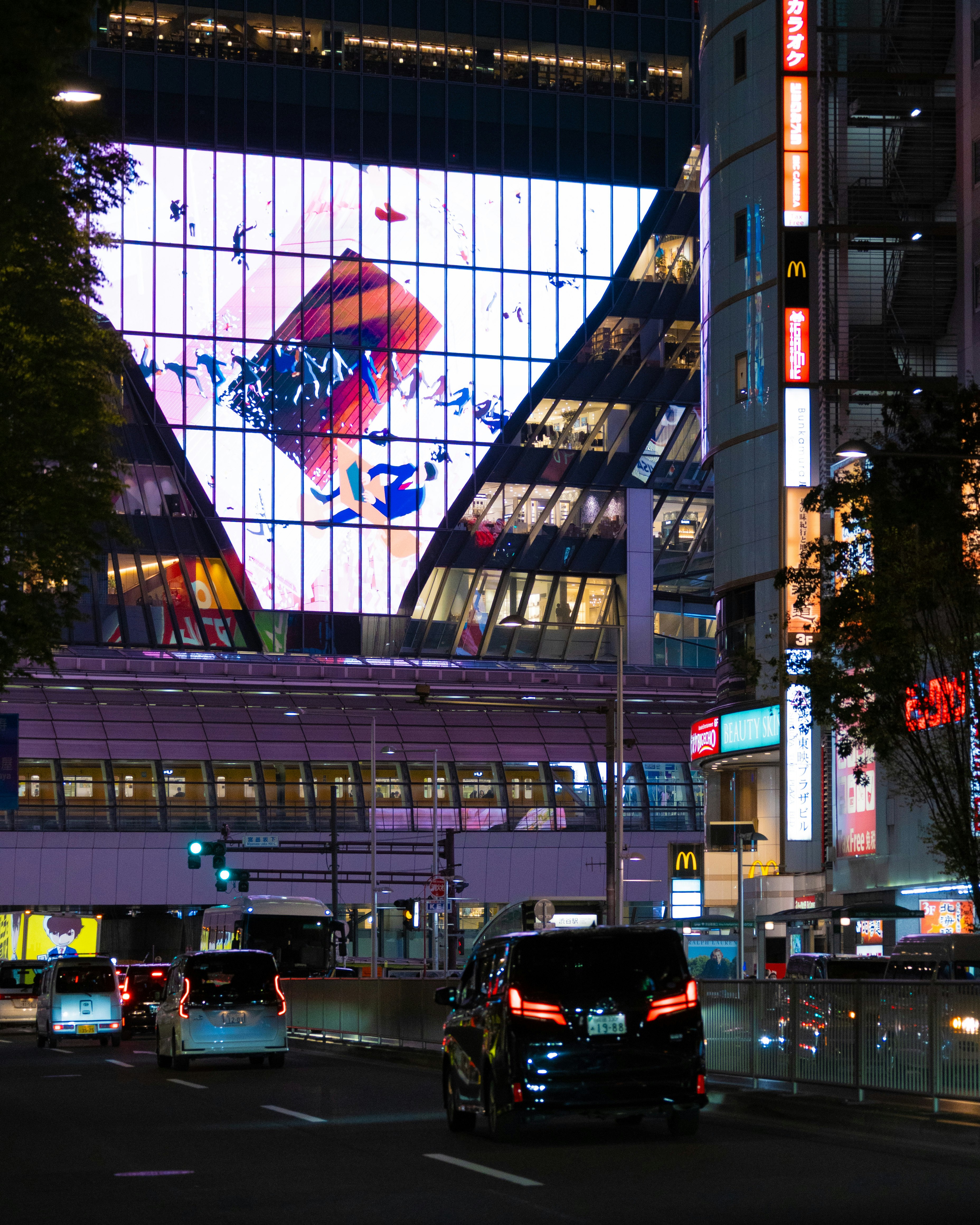 夜の大通りを走る車とビルのネオン看板のある都市景観