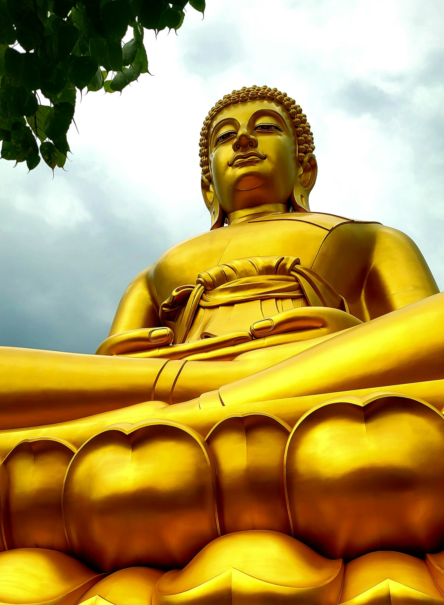 Estatua de Buda dorada sentada con un cielo nublado de fondo