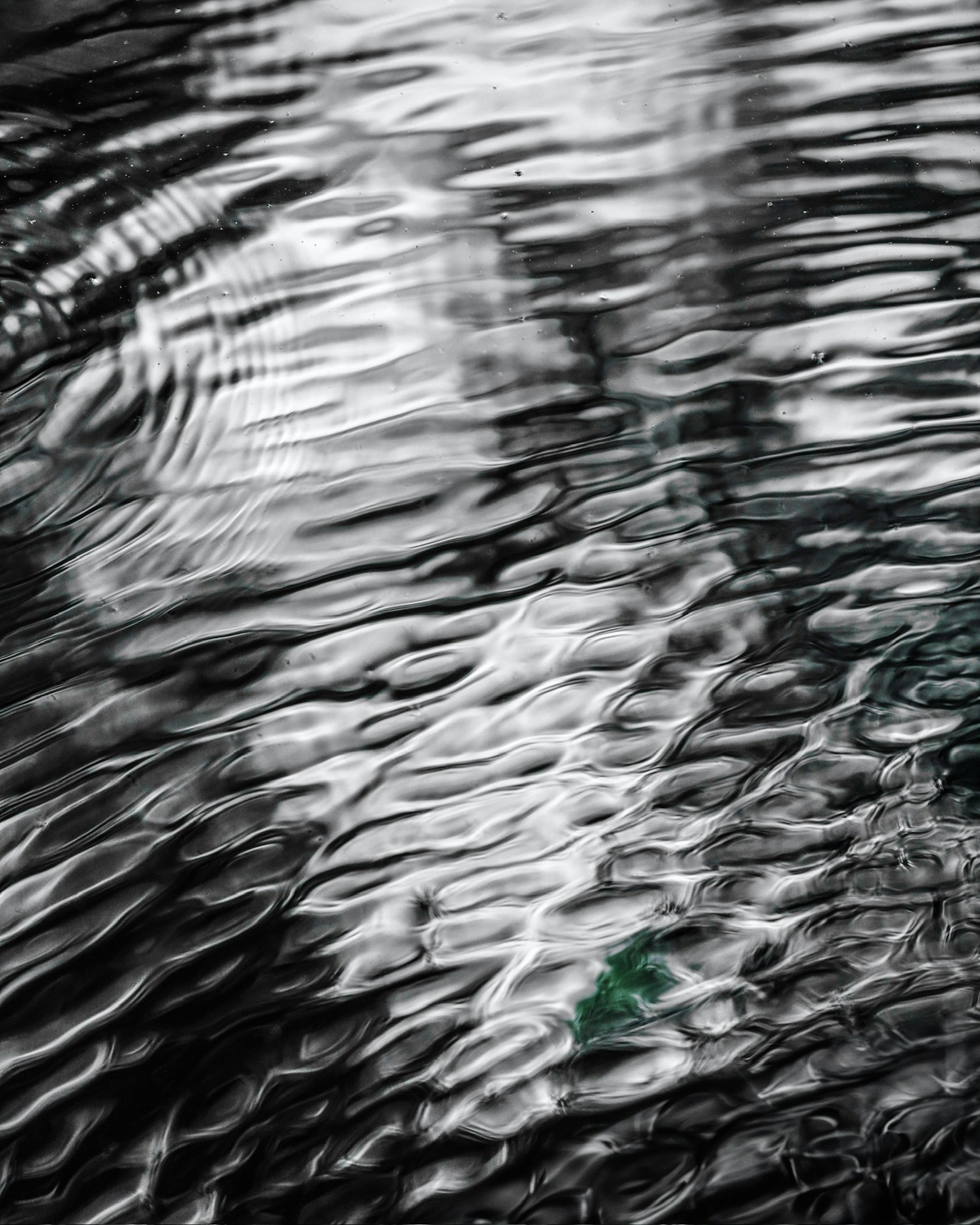 Fotografía en blanco y negro que muestra ondas y reflejos en la superficie del agua